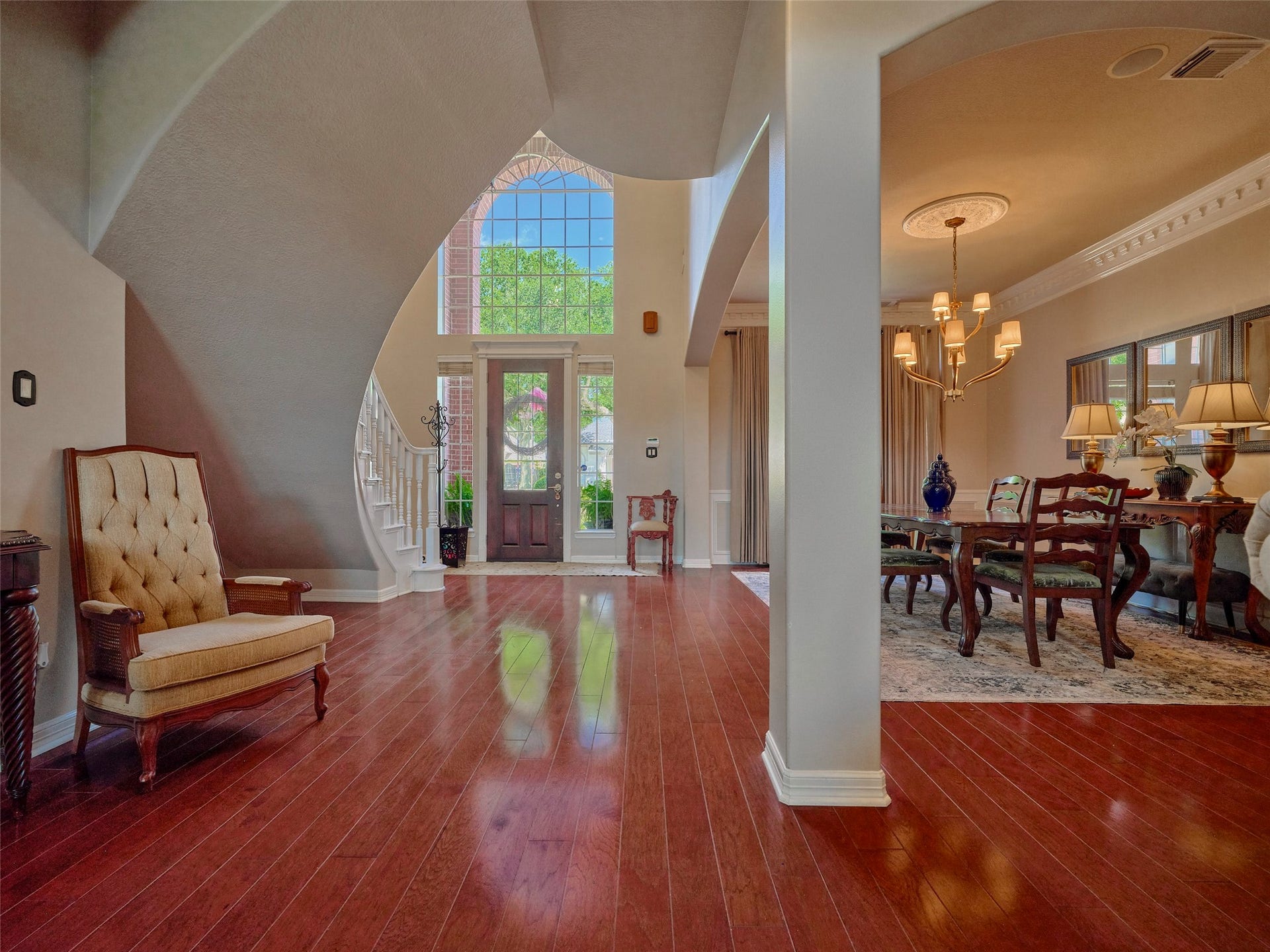 7111 Mohave Hills, Houston, TX 77069 Elegant entryway with a grand staircase, rich wood flooring, and a view into a sophisticated dining area adorned with tasteful lighting and decor.