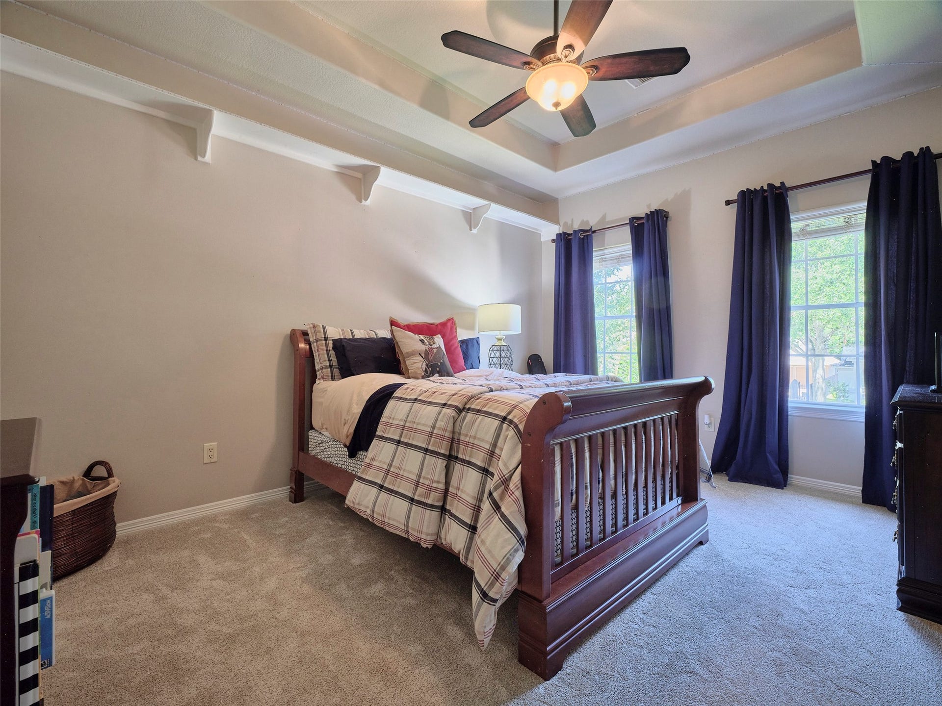 7111 Mohave Hills, Houston, TX 77069 Spacious bedroom featuring a cozy bed, elegant tray ceiling with a fan, and abundant natural light from large windows dressed with dark curtains.