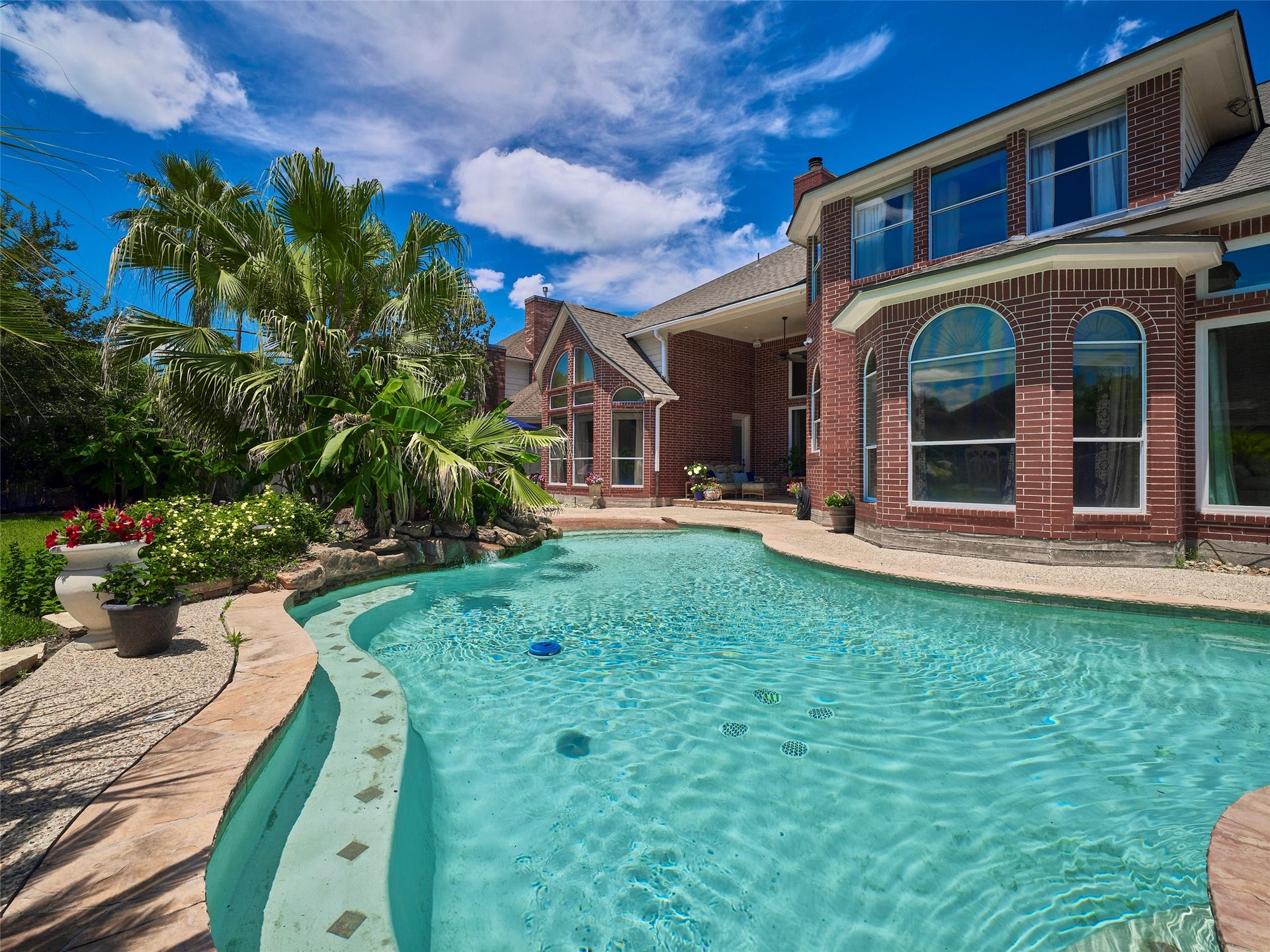 7111 Mohave Hills, Houston, TX 77069 Luxurious backyard oasis featuring a sparkling freeform pool with a spa, surrounded by lush landscaping and ample patio space for relaxation and entertainment.