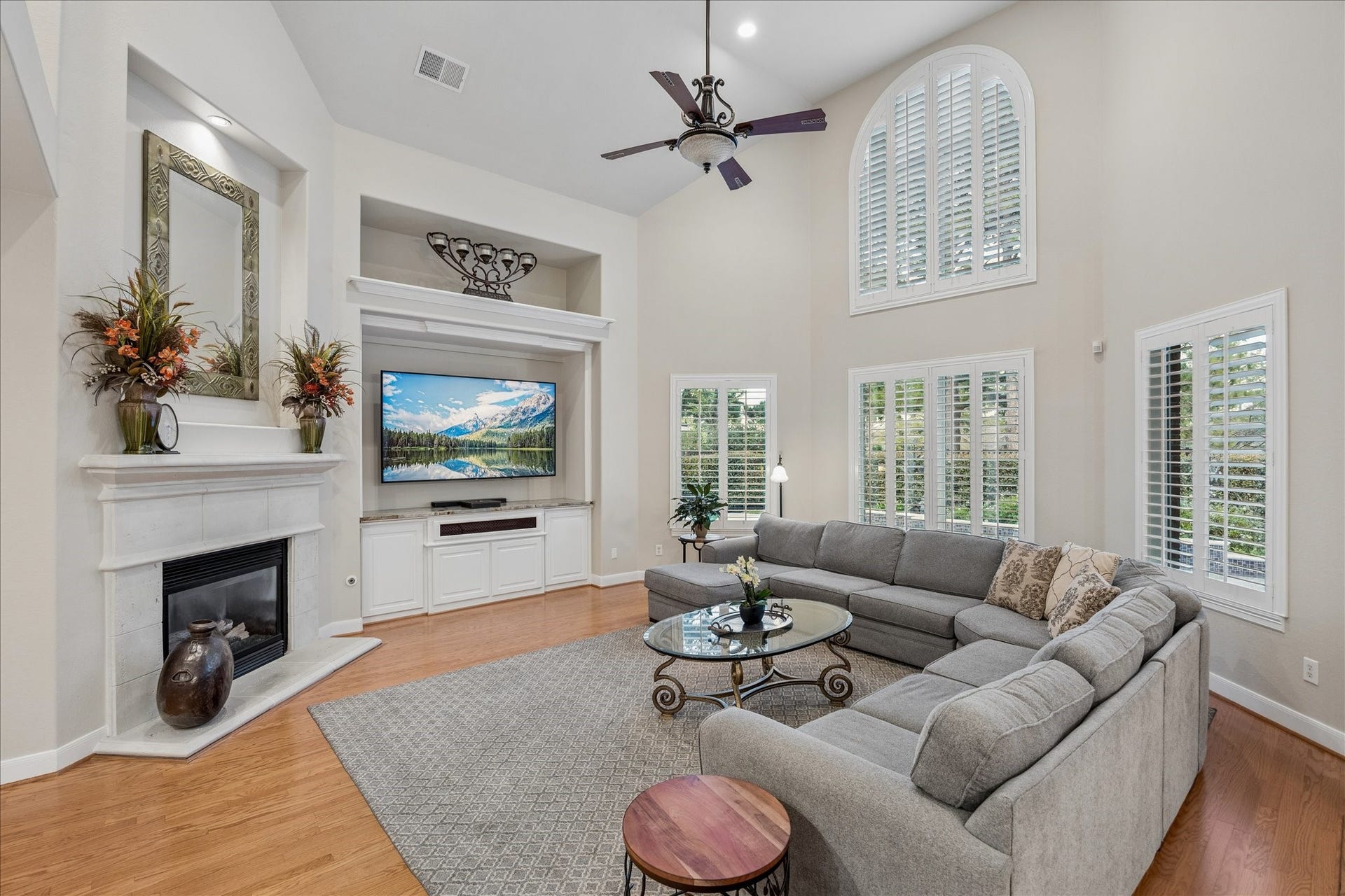 Spacious family room with a tall vaulted ceiling, built-in cabinetry, and a wall of windows overlooking the private backyard and sparkling pool.