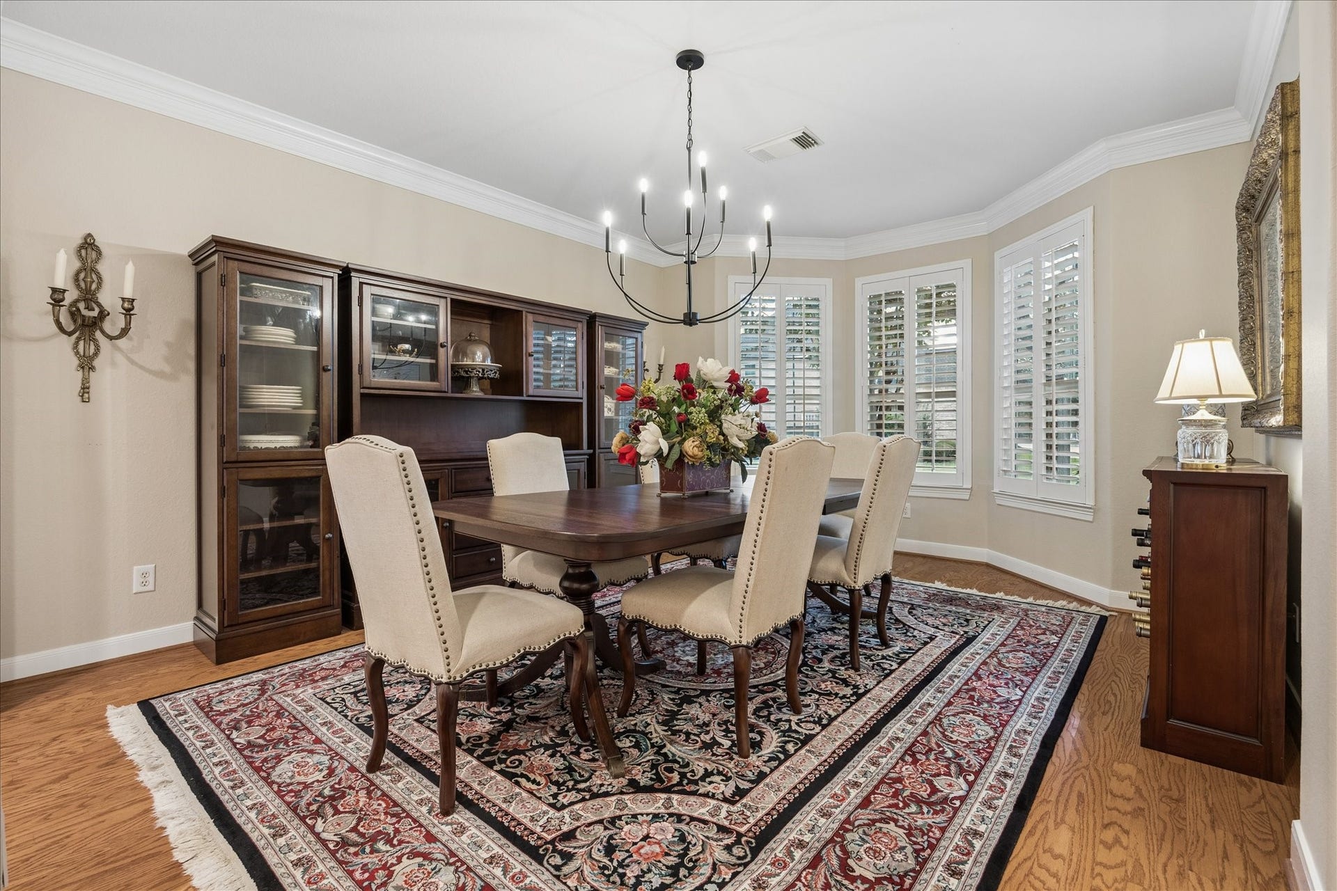 Gather around the dining table for lingering dinners and lively conversation, surrounded by elegant crown molding and beautifully framed windows with plantation shutters.