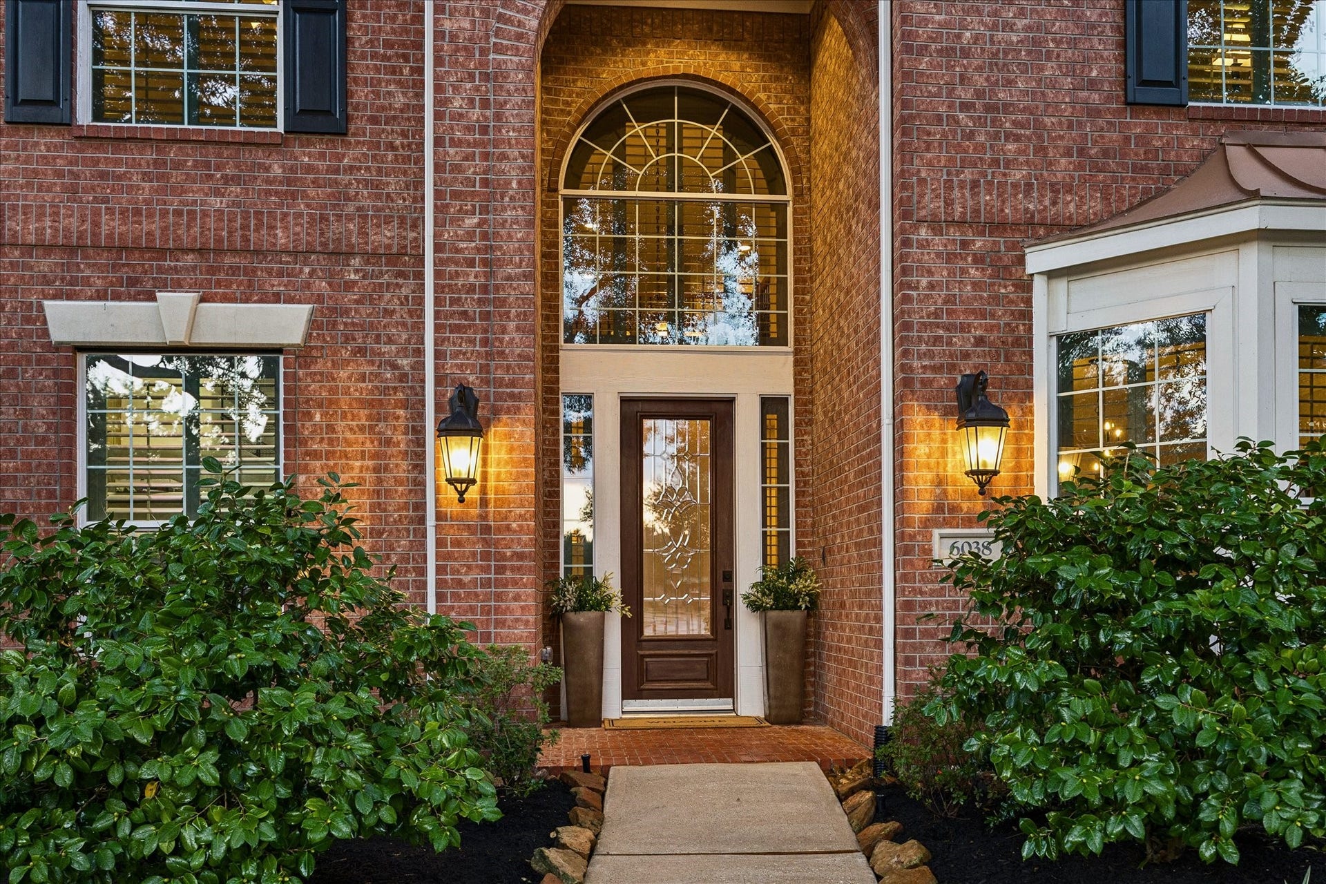 Tall welcoming entry with a large arched window above the front door with leaded glass.