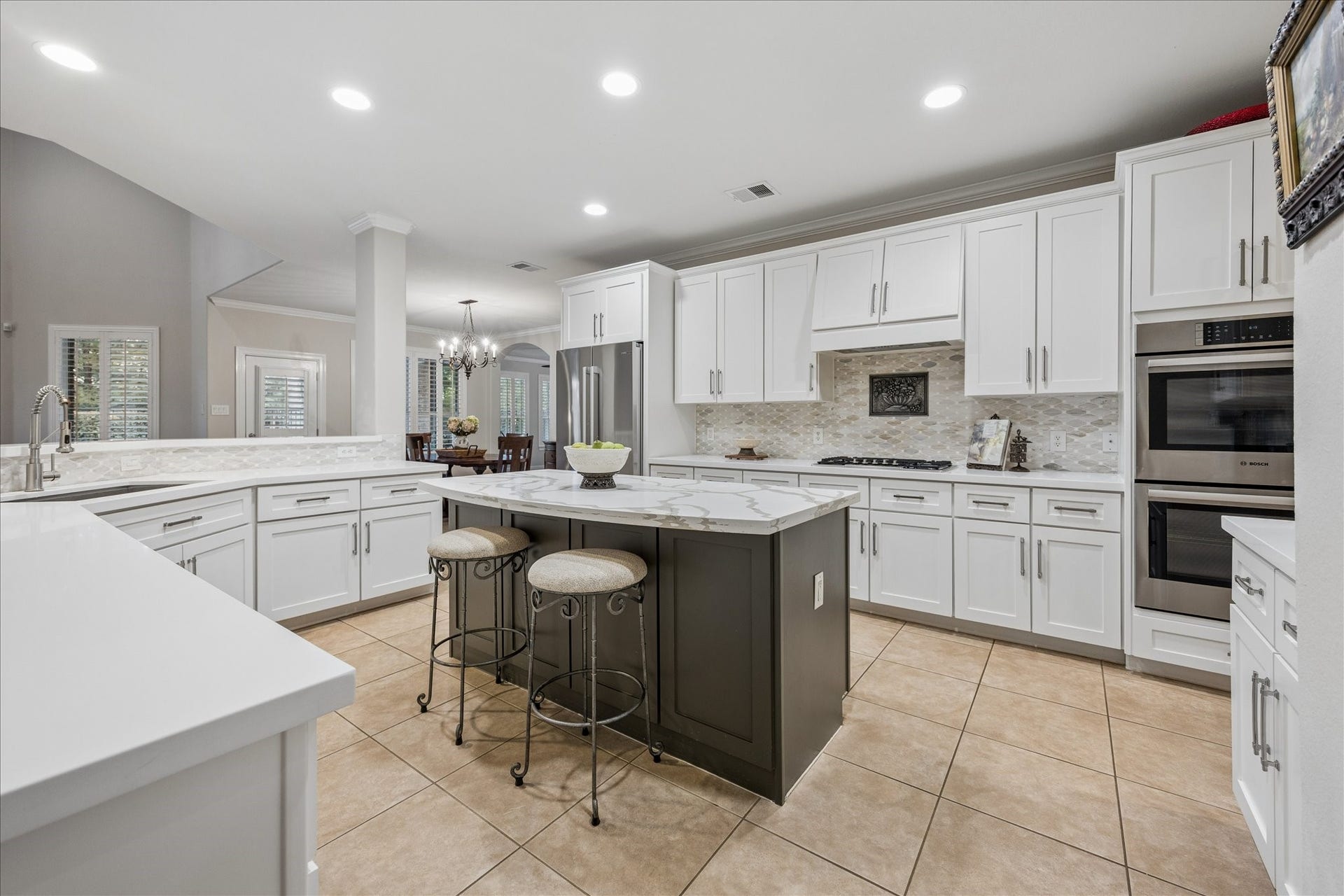 Updated in 2020, this inviting island kitchen features double ovens, quartz countertops, stylish backsplash, and updated hardware; seamlessly flowing into the adjoining living spaces.