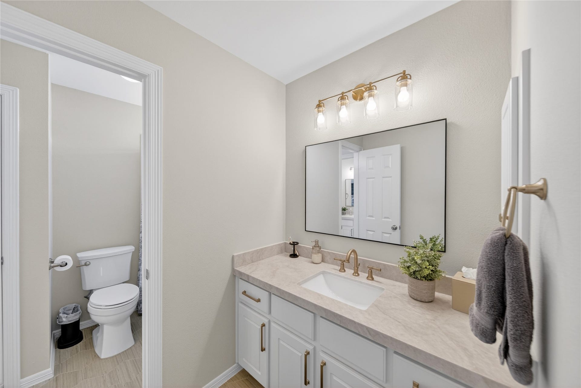 8826 Crown Jewel Drive, Richmond, TX 77469 Modern bathroom featuring a sleek vanity with ample storage, elegant lighting, and a large mirror. Neutral tones create a calming atmosphere, with a separate toilet area for added privacy.