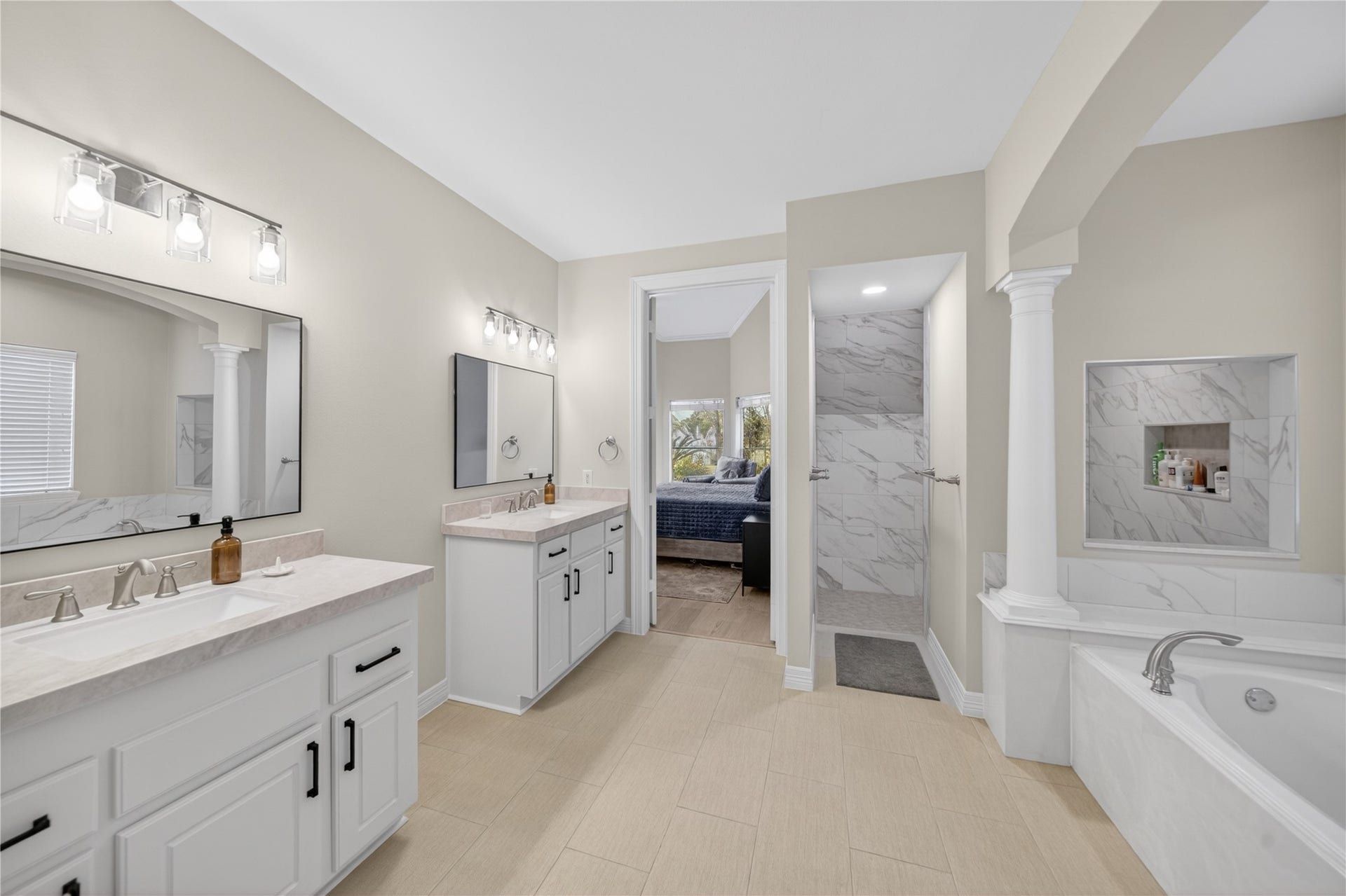 8826 Crown Jewel Drive, Richmond, TX 77469 This spacious bathroom features dual sinks with elegant fixtures, a large mirror, a soaking tub, and a walk-in shower with marble-style tiling. Neutral tones and ample lighting create a bright, inviting space.