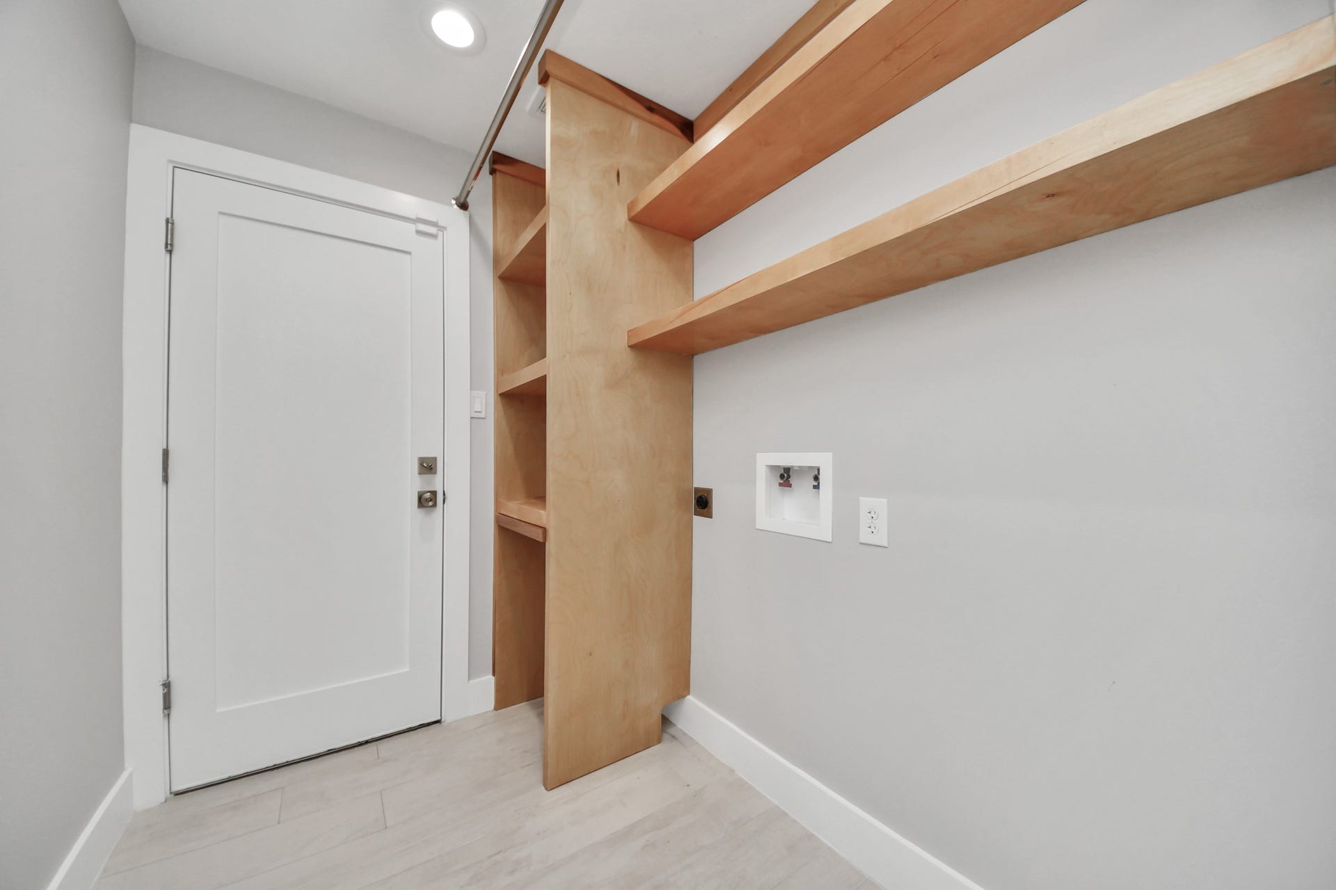 Utility foom with solid wood shelving and entrance to the garage