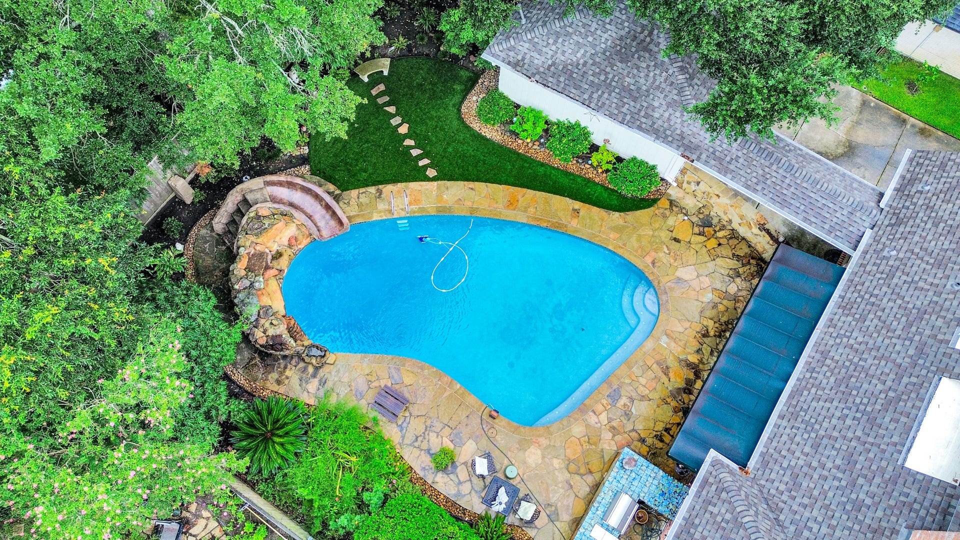 722 Chevy Chase Circle, Sugar Land, TX 77478 The oversized pool features a rock waterfall and slide, with mature landscaping creating a private backyard setting.