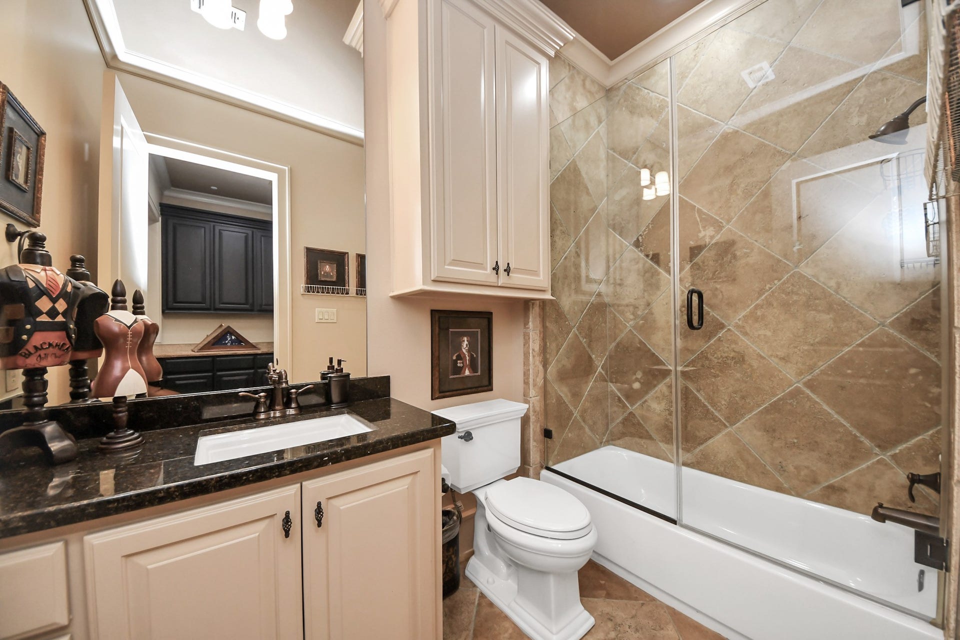 1406 Lake Pointe Parkway, Sugar Land, TX 77478 Well-appointed guest bath conveniently located off of the lower-level office. Tub/shower combo is finished with full-height diagonal tile surround and glass enclosure, creating a polished, cohesive look.