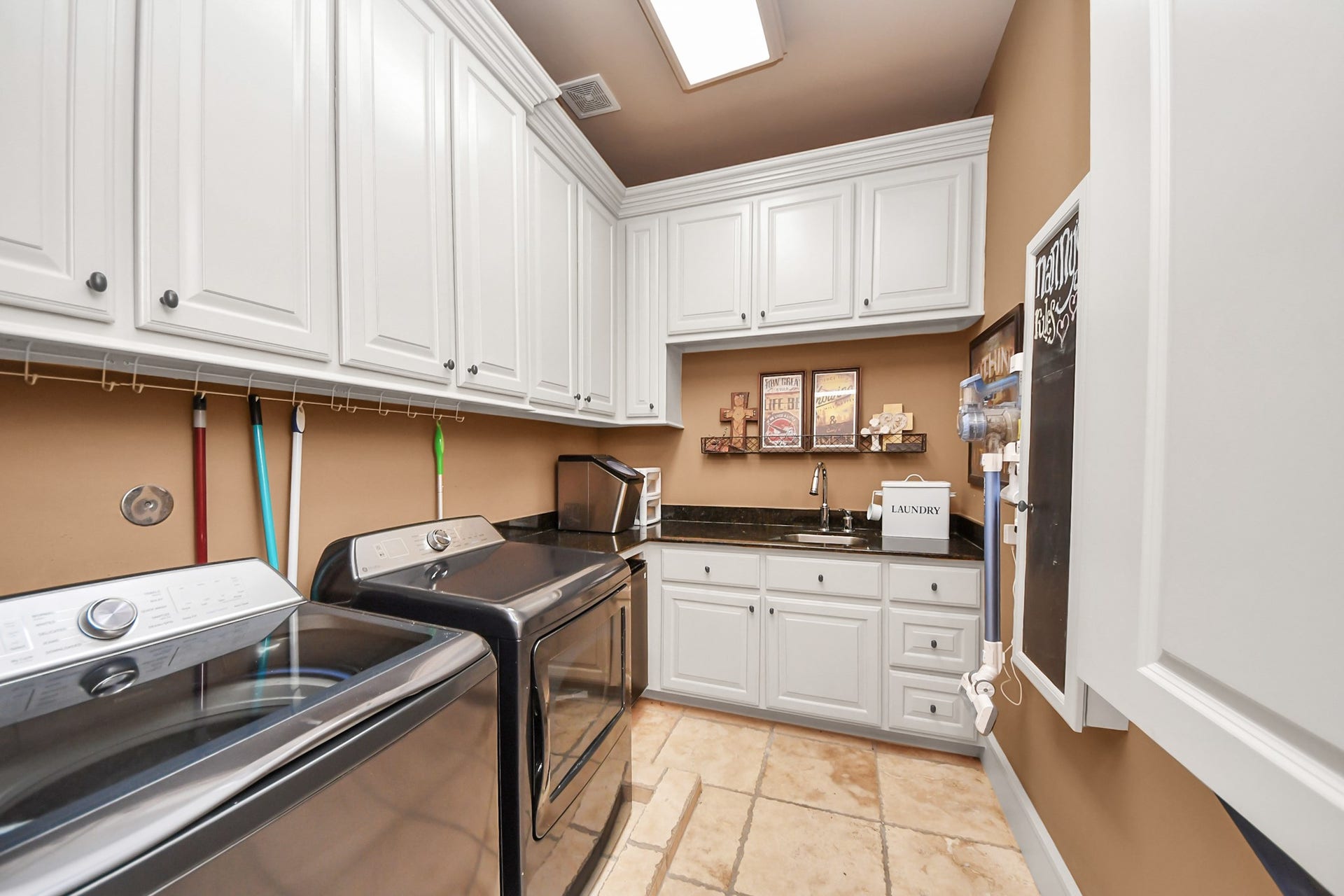 1406 Lake Pointe Parkway, Sugar Land, TX 77478 Charming Dutch door entry leads to a spacious laundry room with abundant cabinetry, built in ironing board, sink, and mini fridge. Thoughtfully designed for maximum storage.