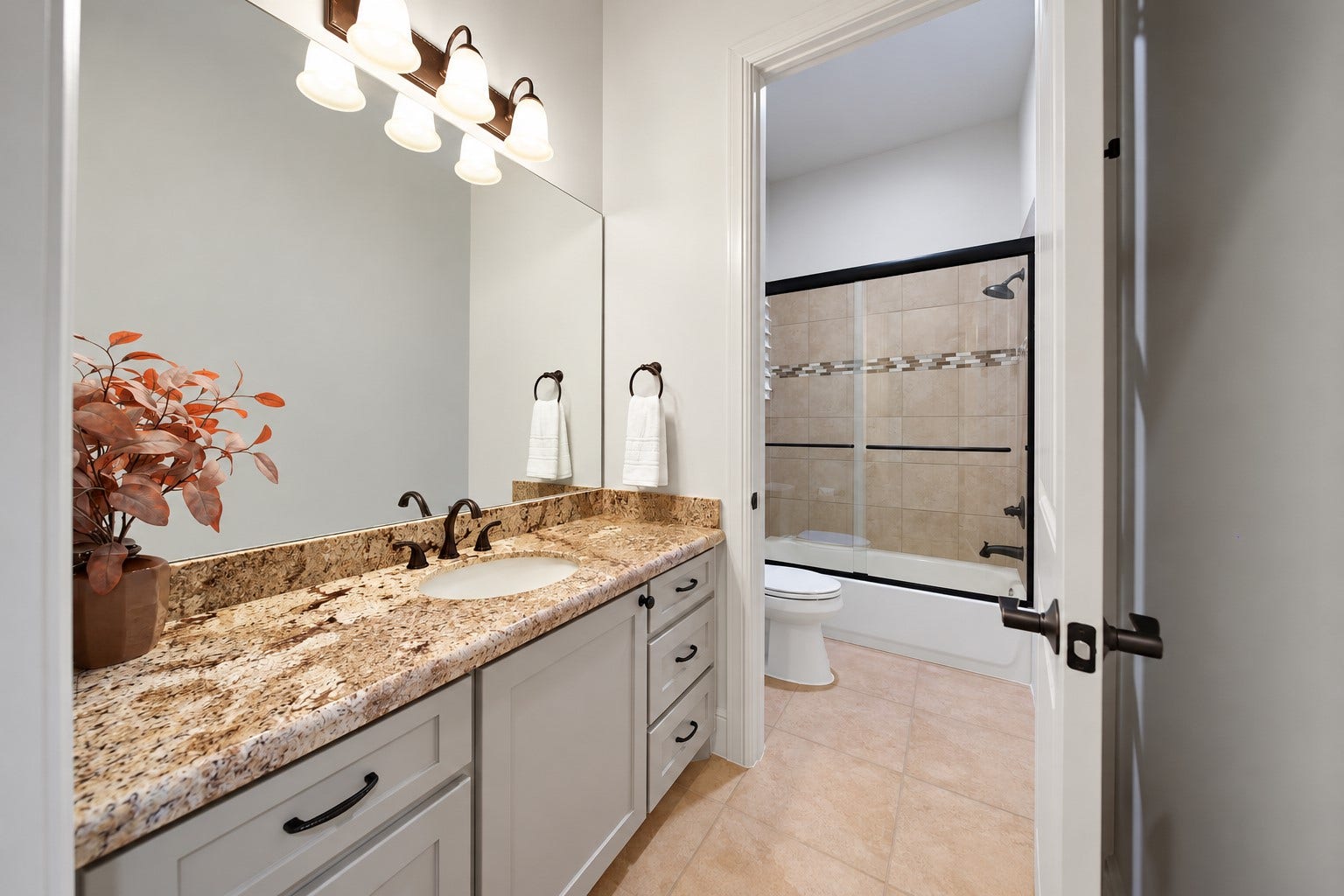 A granite-topped vanity and tiled tub-and-shower combination make daily routines straightforward. The finishes carry the home's cohesive style into this full bathroom.