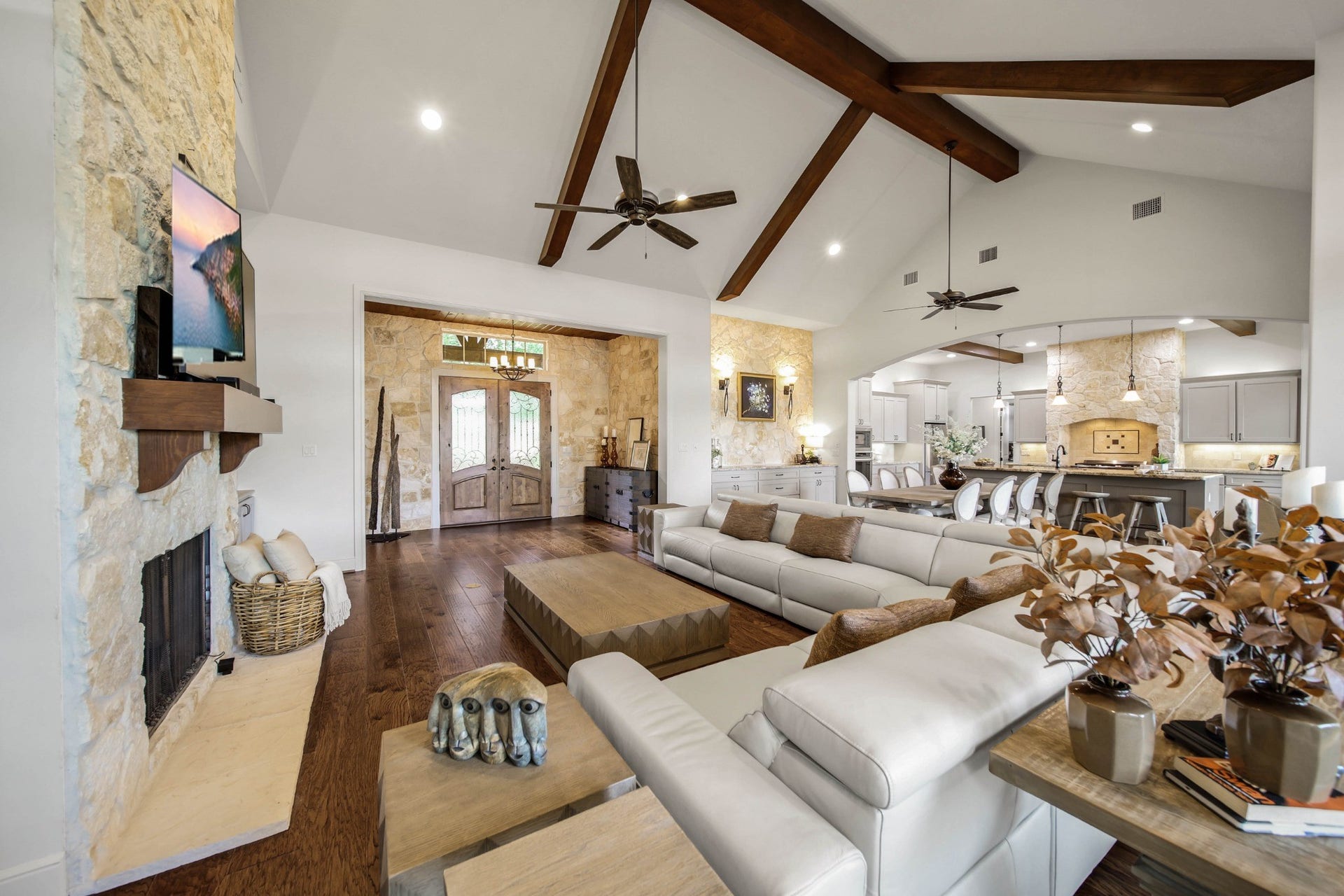 The gathering begins here. A beamed ceiling rises above the living room, while the stone fireplace and adjoining kitchen keep conversation connected from one part of the evening to the next.