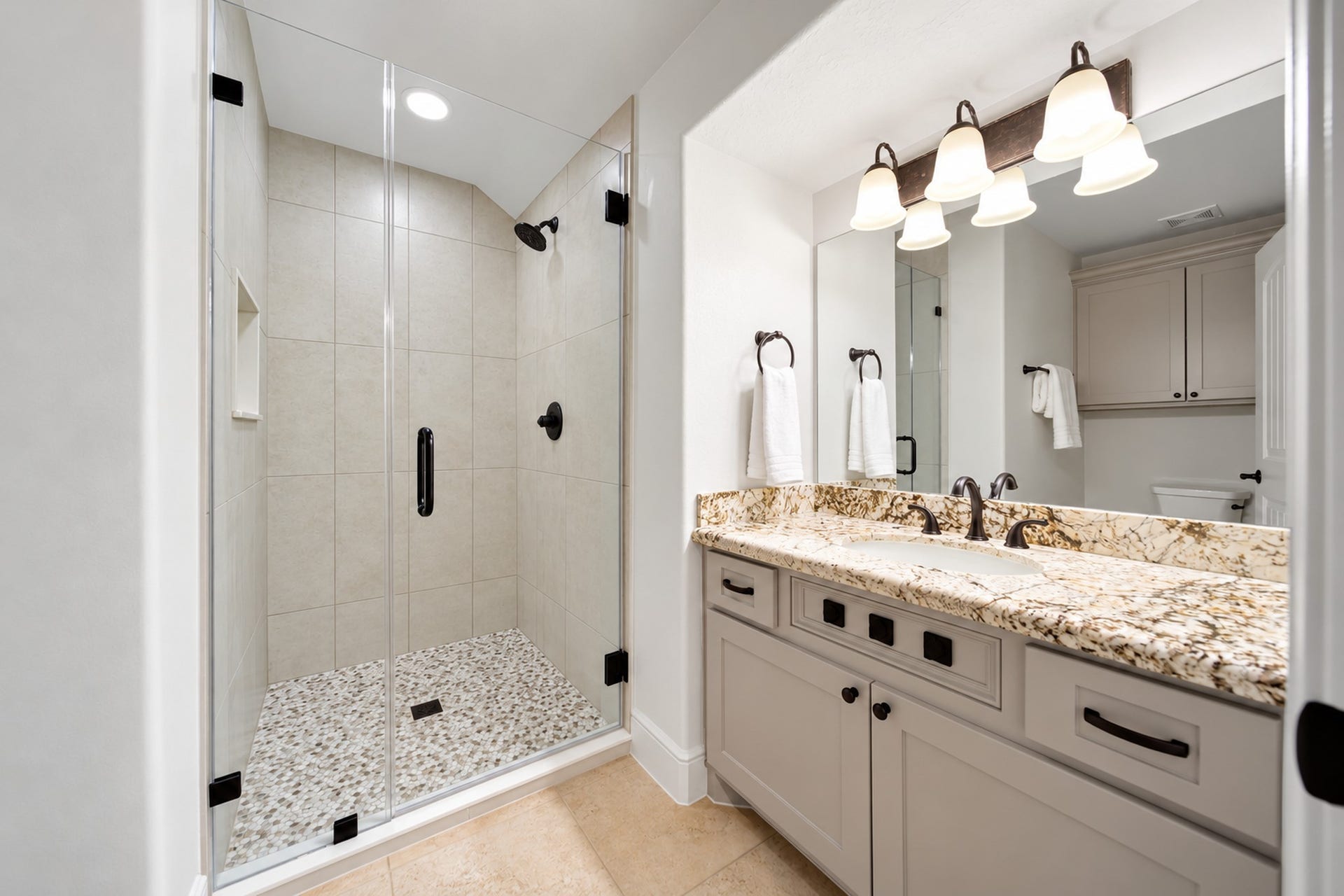 The upstairs bathroom pairs a granite-topped vanity with a tiled shower. It adds convenience to the bedroom and carries the home's finishes through the upper level.