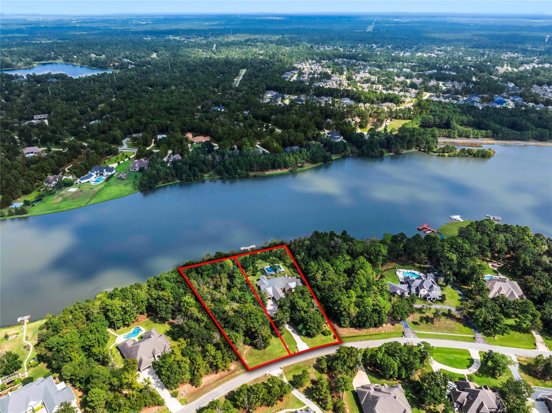 The wider view shows the home's position along the shoreline and the wooded lot beside it. The adjacent lot is separately listed and excluded from this home's acreage. Outlines are approximate.