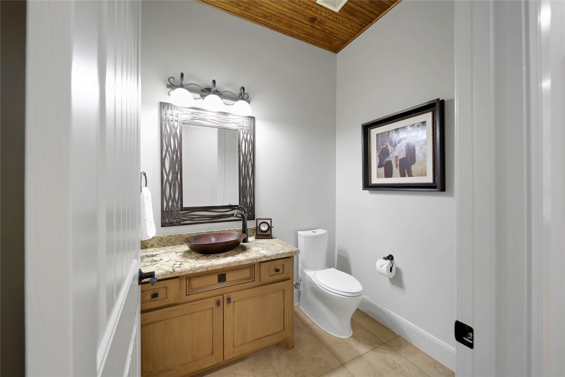 A wood ceiling and stone-topped vanity bring the home's warm finishes into the powder room.