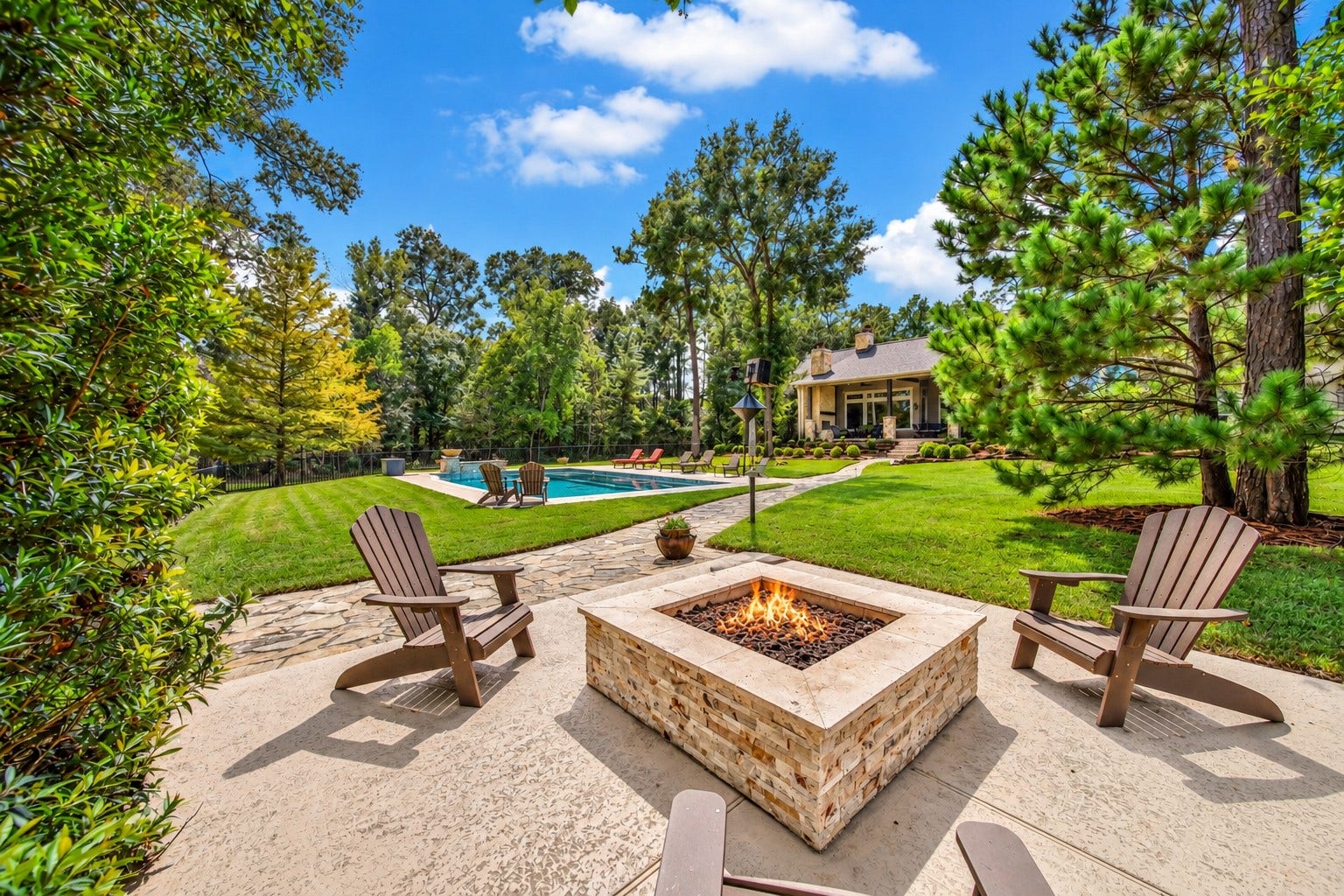 As daylight softens, pull a chair toward the fire pit. This gathering spot adds another destination to the grounds, with the pool nearby and the home just up the path.