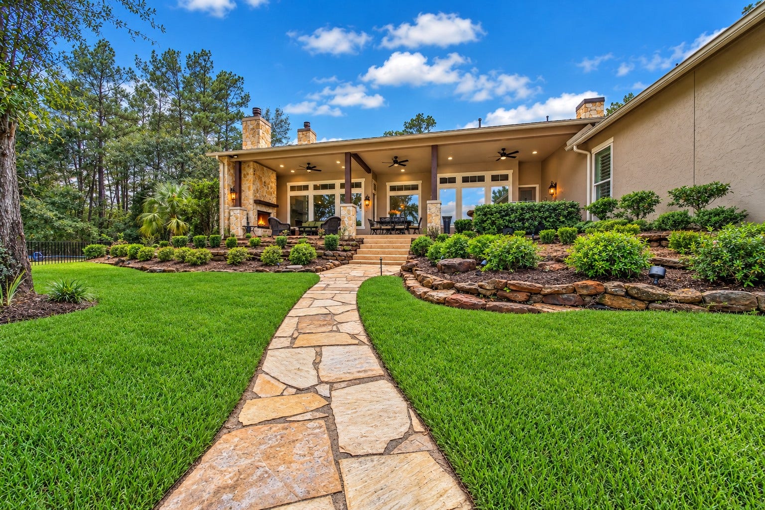 Follow the stone path back toward the house, where layered landscaping leads to the covered patio. The grounds connect the home, pool and lakefront into one inviting outdoor experience.