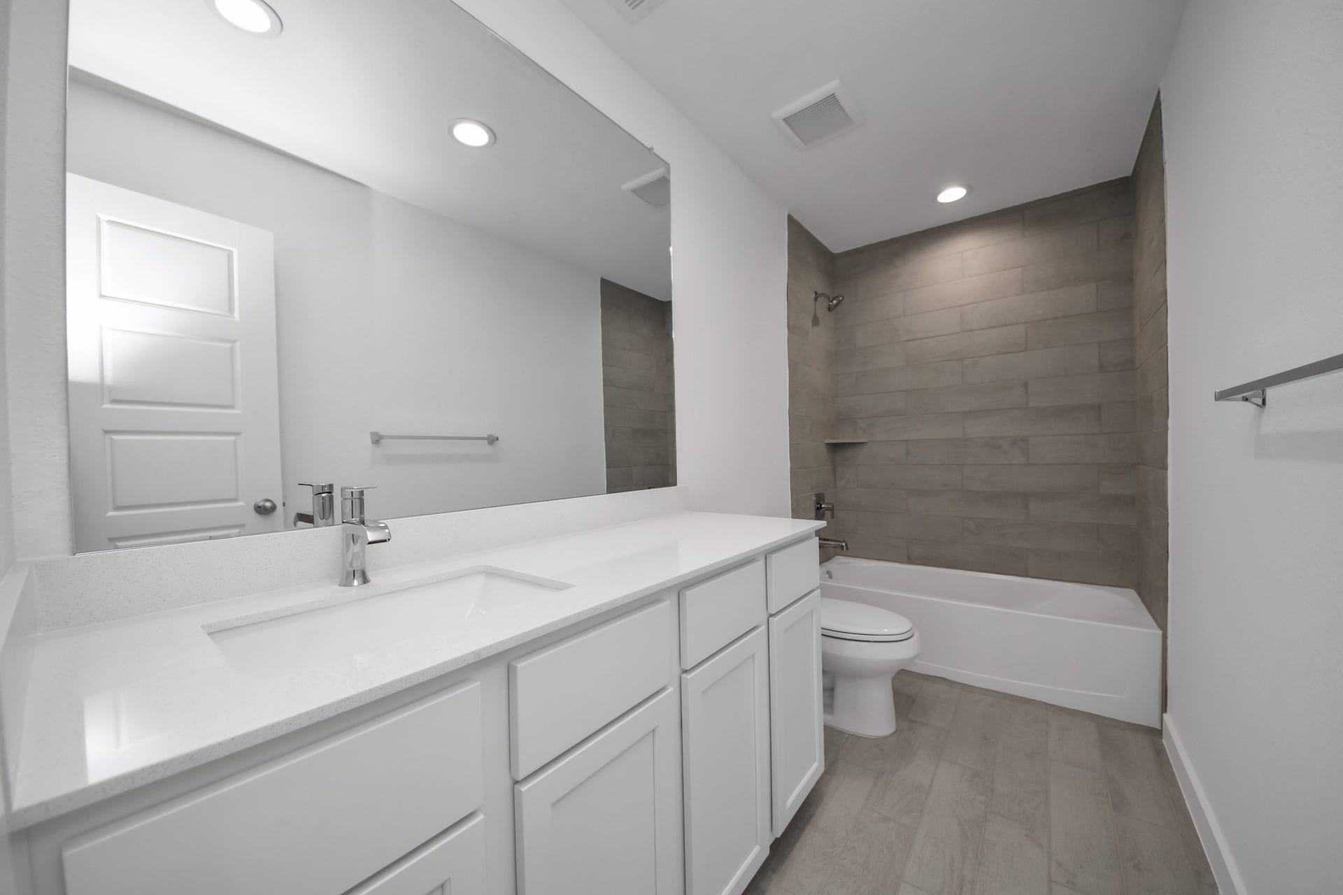 11015 Hosta Stream Drive, Houston, TX 77044 Secondary bath features tile flooring, bath/shower combo with tile surround, light stained wood cabinets, beautiful light countertop. Sample photo of completed home with similar floor plan. Actual colors and selections may vary.