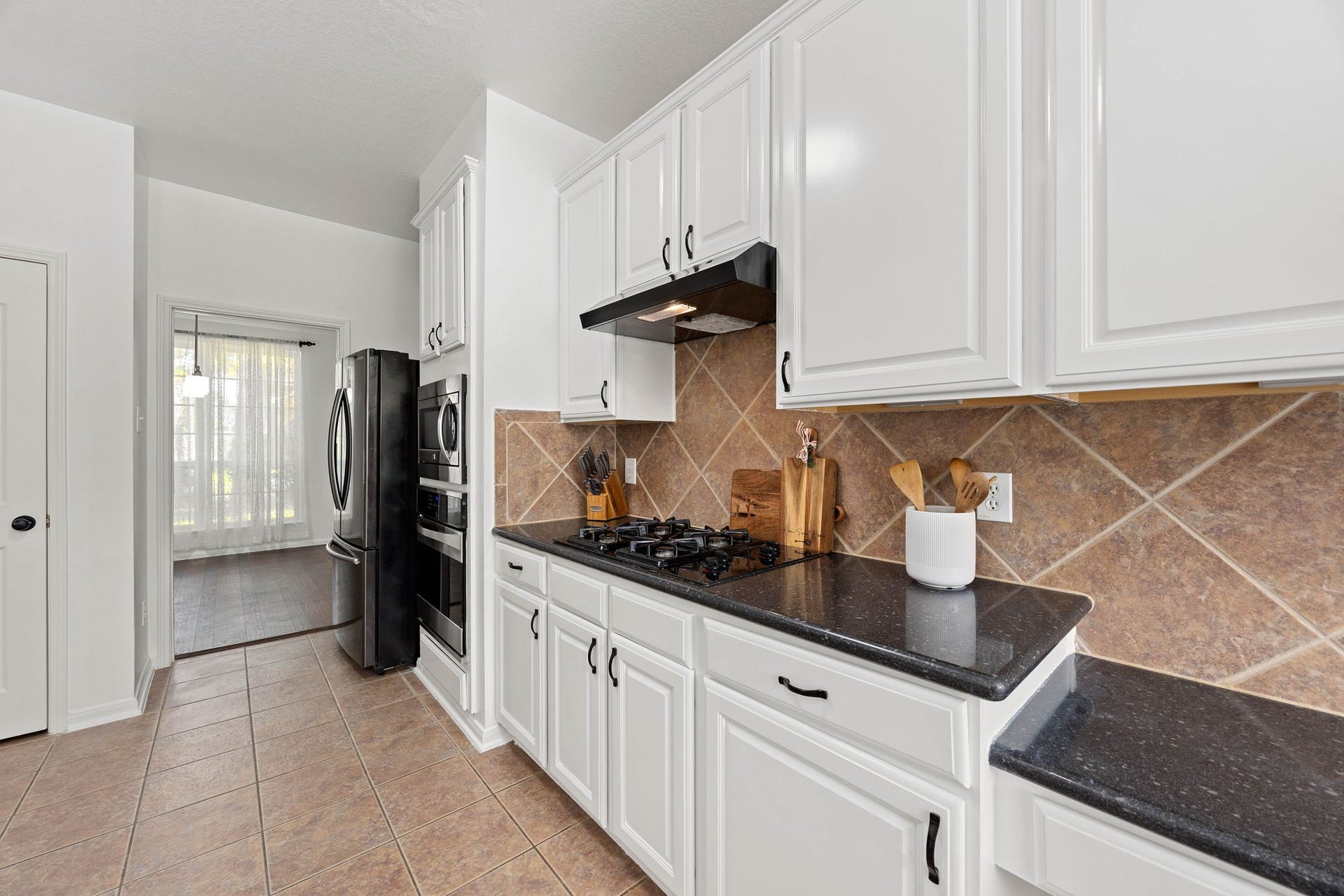4730 Camden Brook Lane, Katy, TX 77494 Kitchen view highlighting abundant white cabinetry, extensive countertop space, tile backsplash, and appliance area.