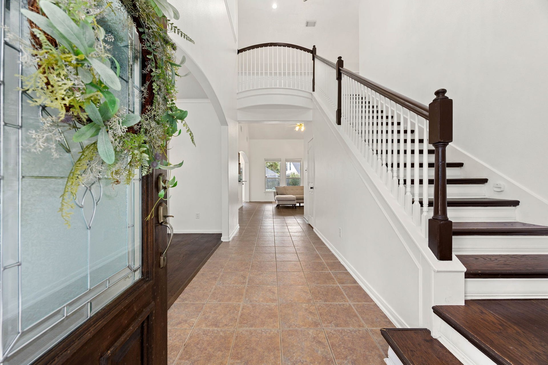 4730 Camden Brook Lane, Katy, TX 77494 Inviting entry hallway featuring wood-look flooring, a staircase with contrasting railing, and a view toward the living areas.