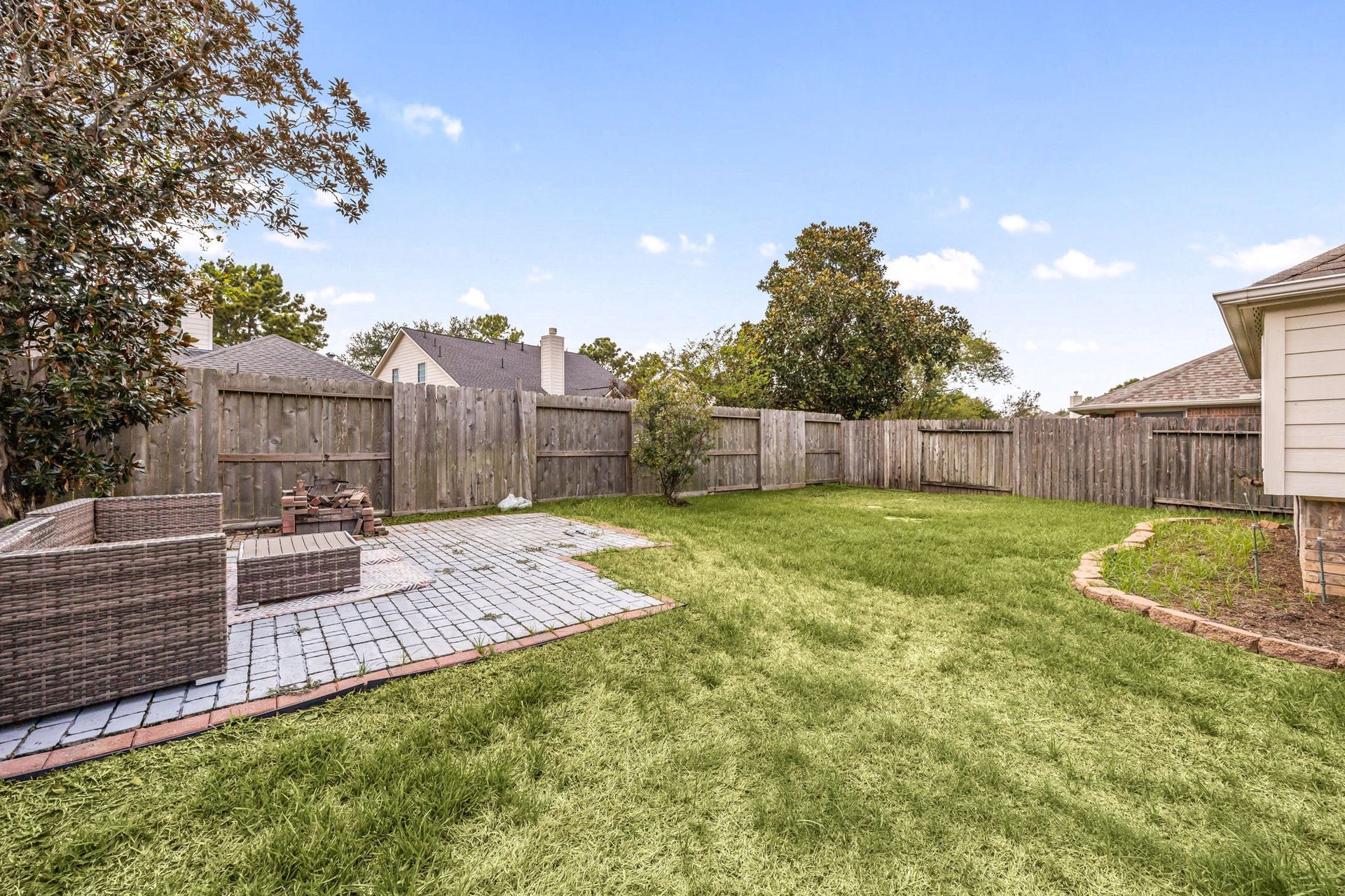 4730 Camden Brook Lane, Katy, TX 77494 Wide backyard view showcasing the homes rear exterior, covered patio, and generous fenced lawn.
