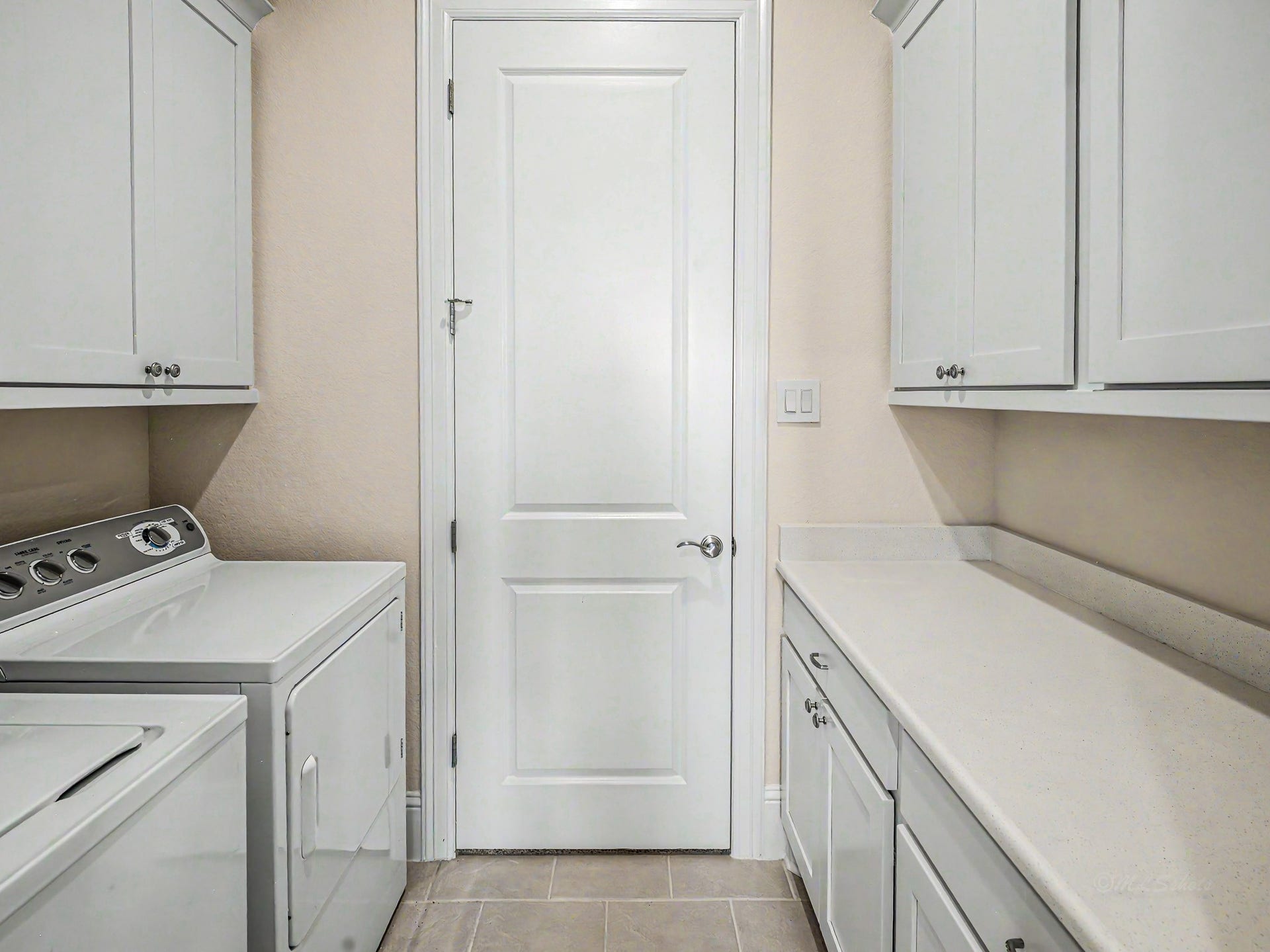 Large utility room with plenty of cabinet space, folding area & washer & dryer.