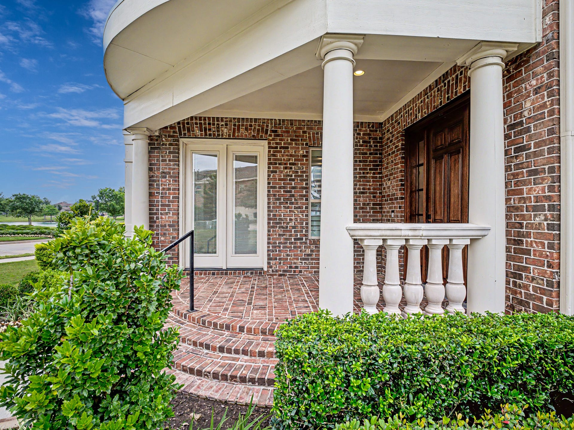 Beautifully bricked front porch with stone accents, stately columns, gorgeous front door adds depth & warmth to the home.