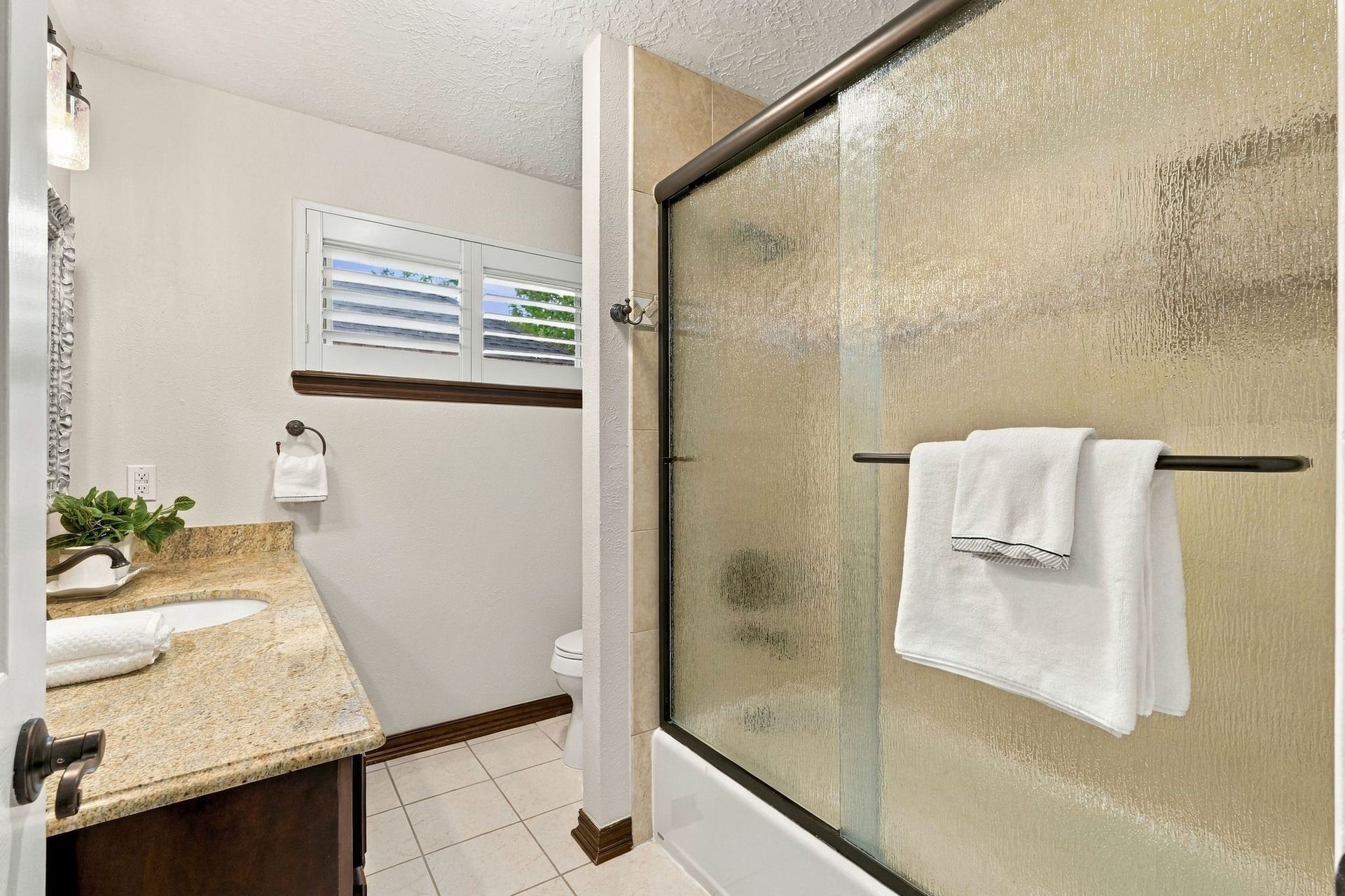 8 Diamond Oak Court, The Woodlands, TX 77381 Bathroom featuring a glass-enclosed combination tub & shower, spacious vanity, and neutral finishes.