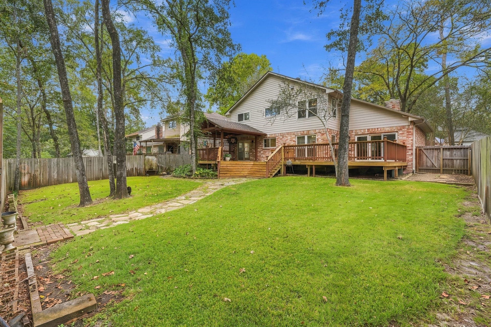 8 Diamond Oak Court, The Woodlands, TX 77381 Spacious backyard featuring a large green lawn, mature shade trees, and plenty of room for outdoor activities. Check out the expansive deck!