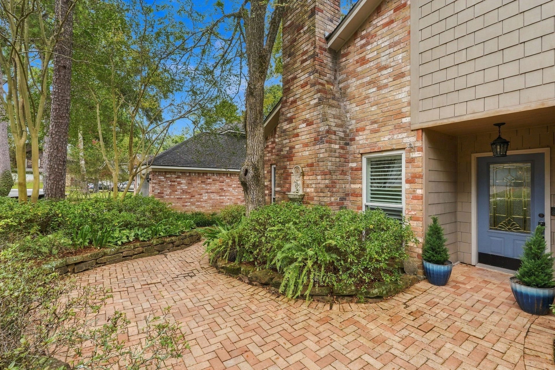 8 Diamond Oak Court, The Woodlands, TX 77381 Another view of the home's exterior, highlighting the mature trees, brick accents, and landscaped walkway.
