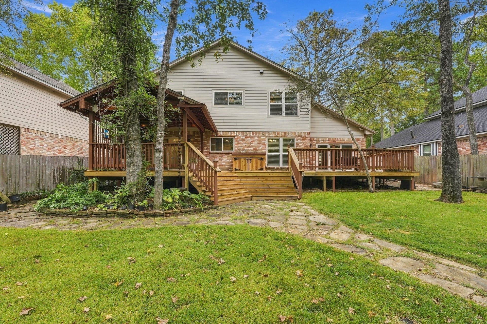 8 Diamond Oak Court, The Woodlands, TX 77381 Rear exterior view of the home, highlighting the large wooden deck and beautifully maintained backyard.