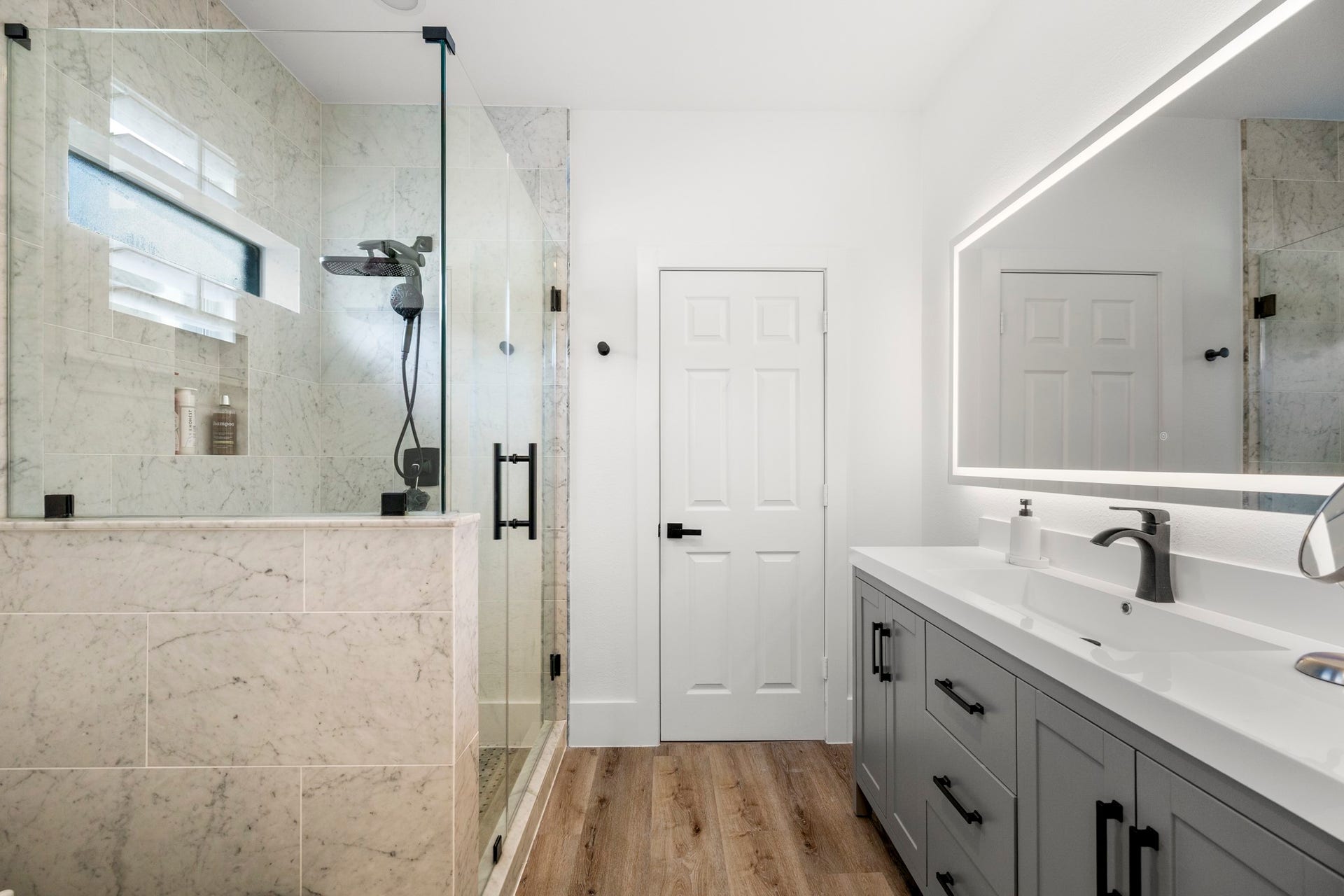 31219 Edgewater Drive, Magnolia, TX 77354 The adjoining bathroom has a double-sink vanity, an illuminated mirror and a glass-enclosed shower.