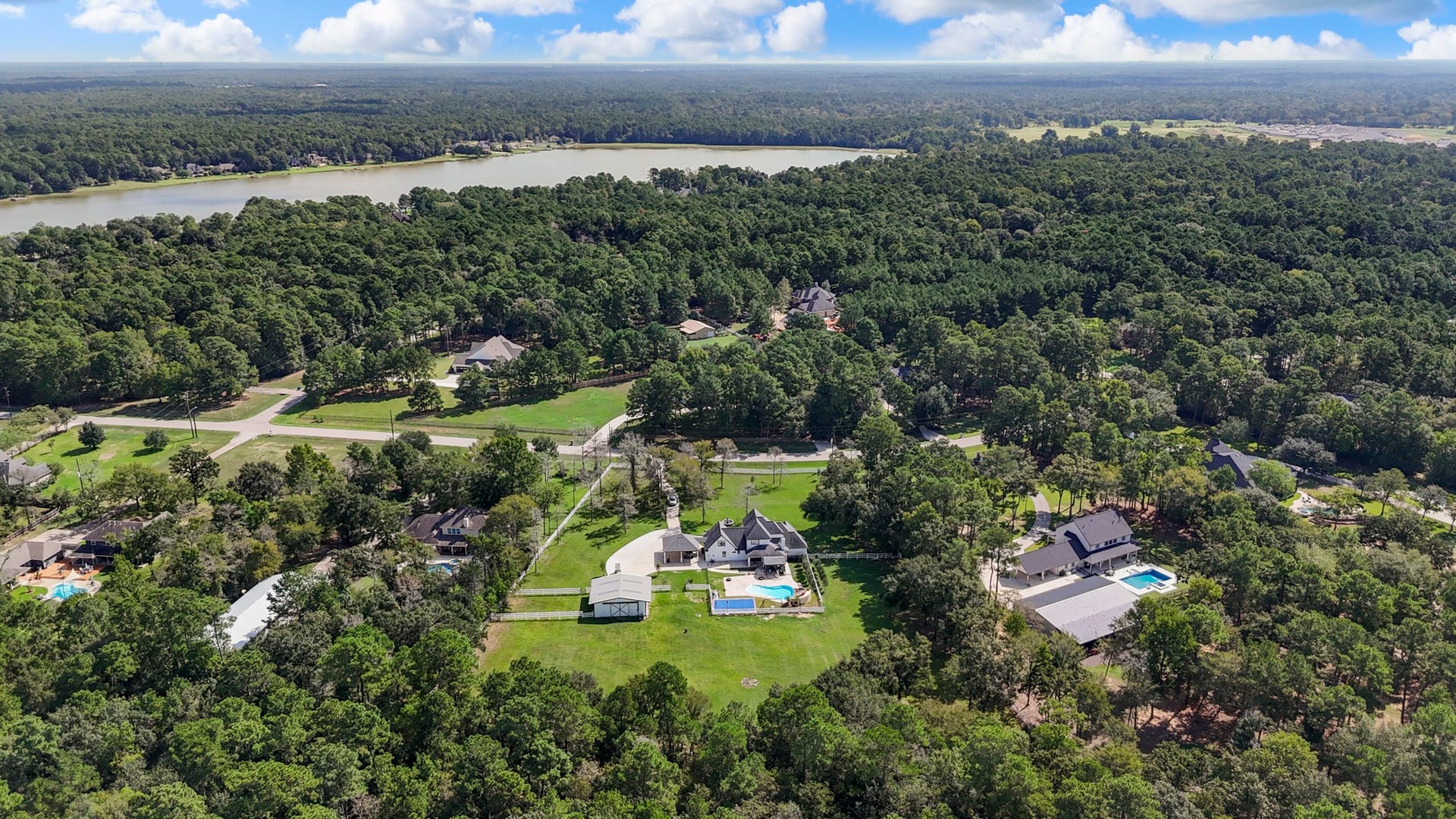 31219 Edgewater Drive, Magnolia, TX 77354 A wider view places the property among the surrounding trees, with a nearby lake in the distance.