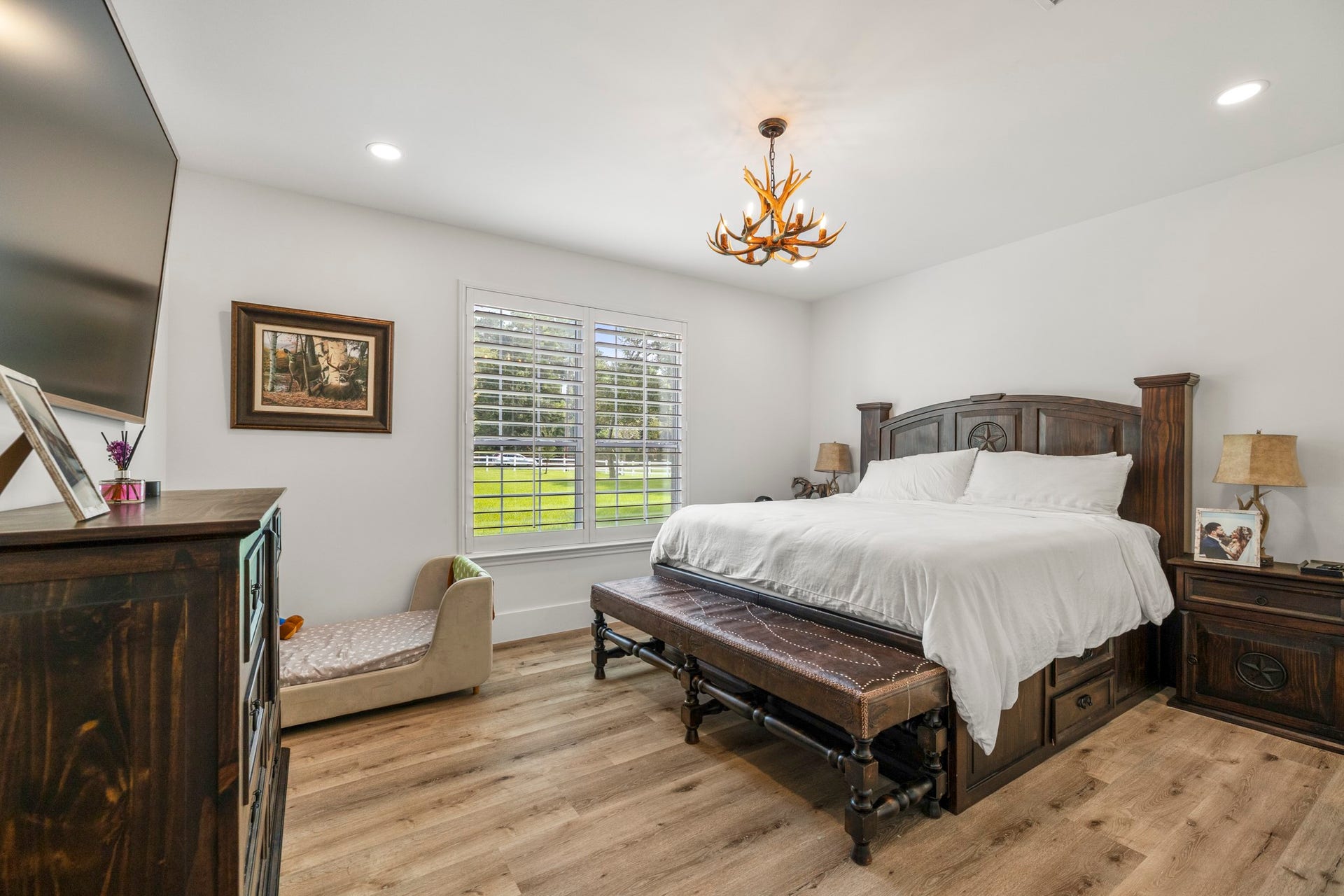 31219 Edgewater Drive, Magnolia, TX 77354 The primary suite offers a spacious retreat with wood flooring, recessed lighting and a shuttered window overlooking the grounds.