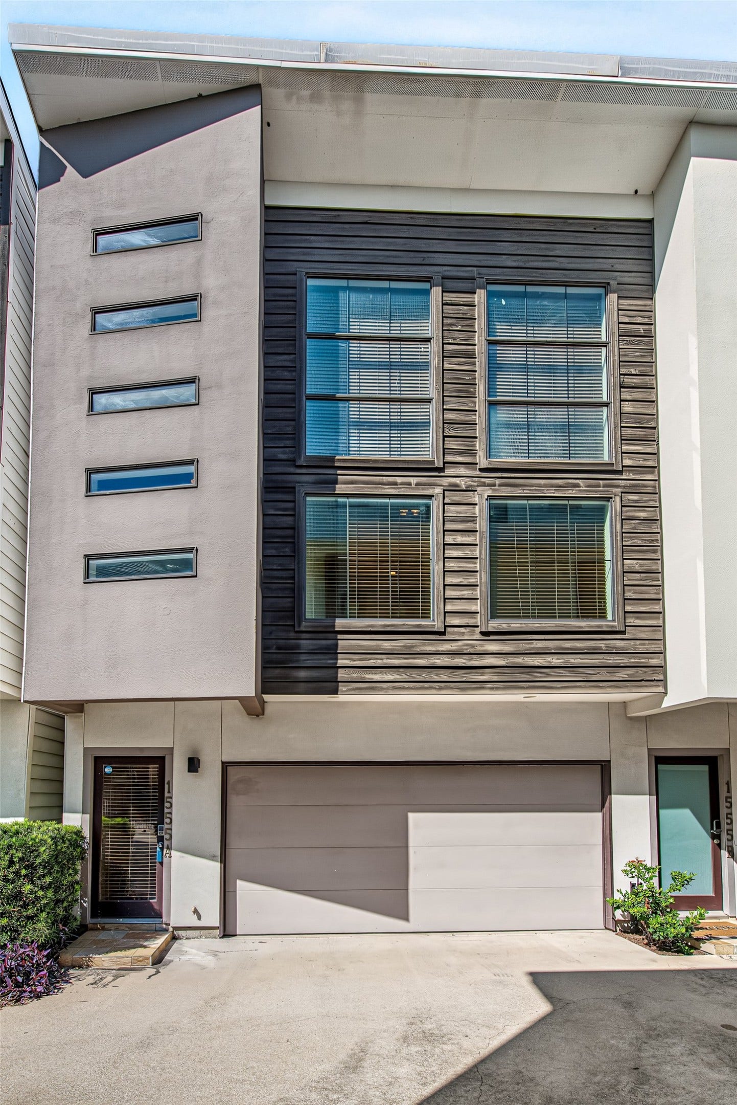 1555 Birdsall Street, #A, Houston, TX 77007 As you enter through the secure automatic driveway gate, this home makes a striking impression with its bold modern silhouette, crisp clean lines, and architectural depth. The facade showcases an artistic blend of materials, featuring smooth taupe-toned stucco set against horizontal dark wood accents that add rich texture and warmth.