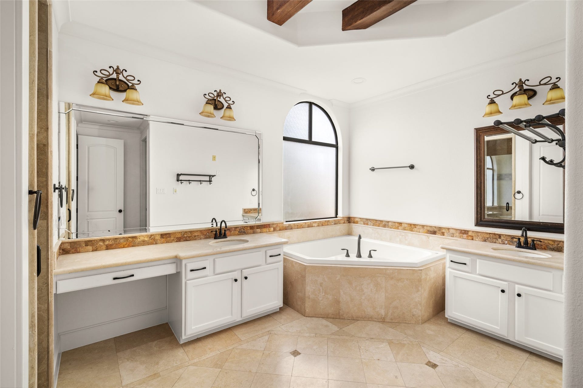 5218 Feagan Street, #D, Houston, TX 77007 Spacious primary bathroom featuring dual vanities, white cabinetry, a corner soaking tub, and elegant stone tile finishes.