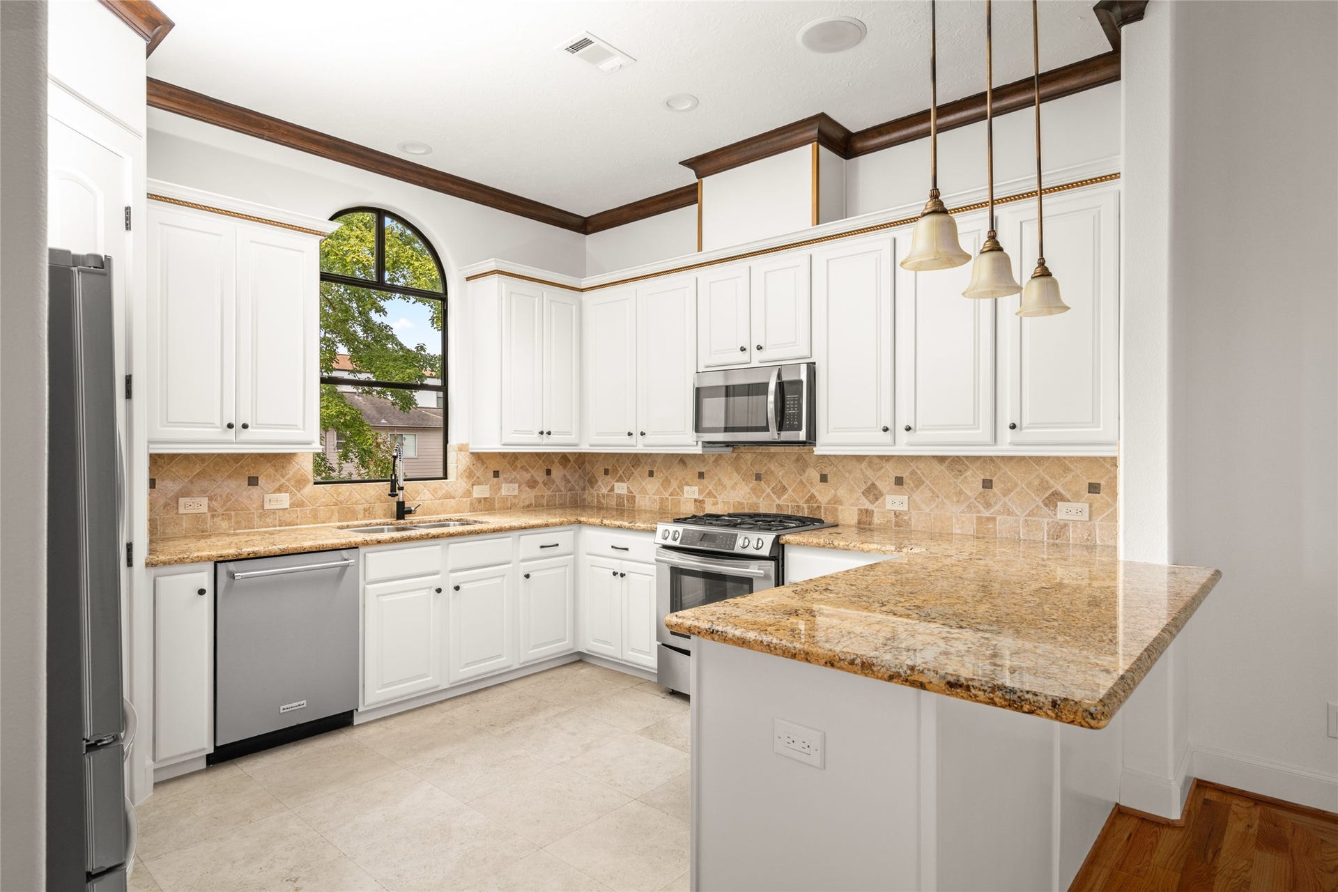 5218 Feagan Street, #D, Houston, TX 77007 Second floor- Spacious kitchen with stainless steel appliances, travertine flooring, granite countertops, pendant lights, and plenty of storage.