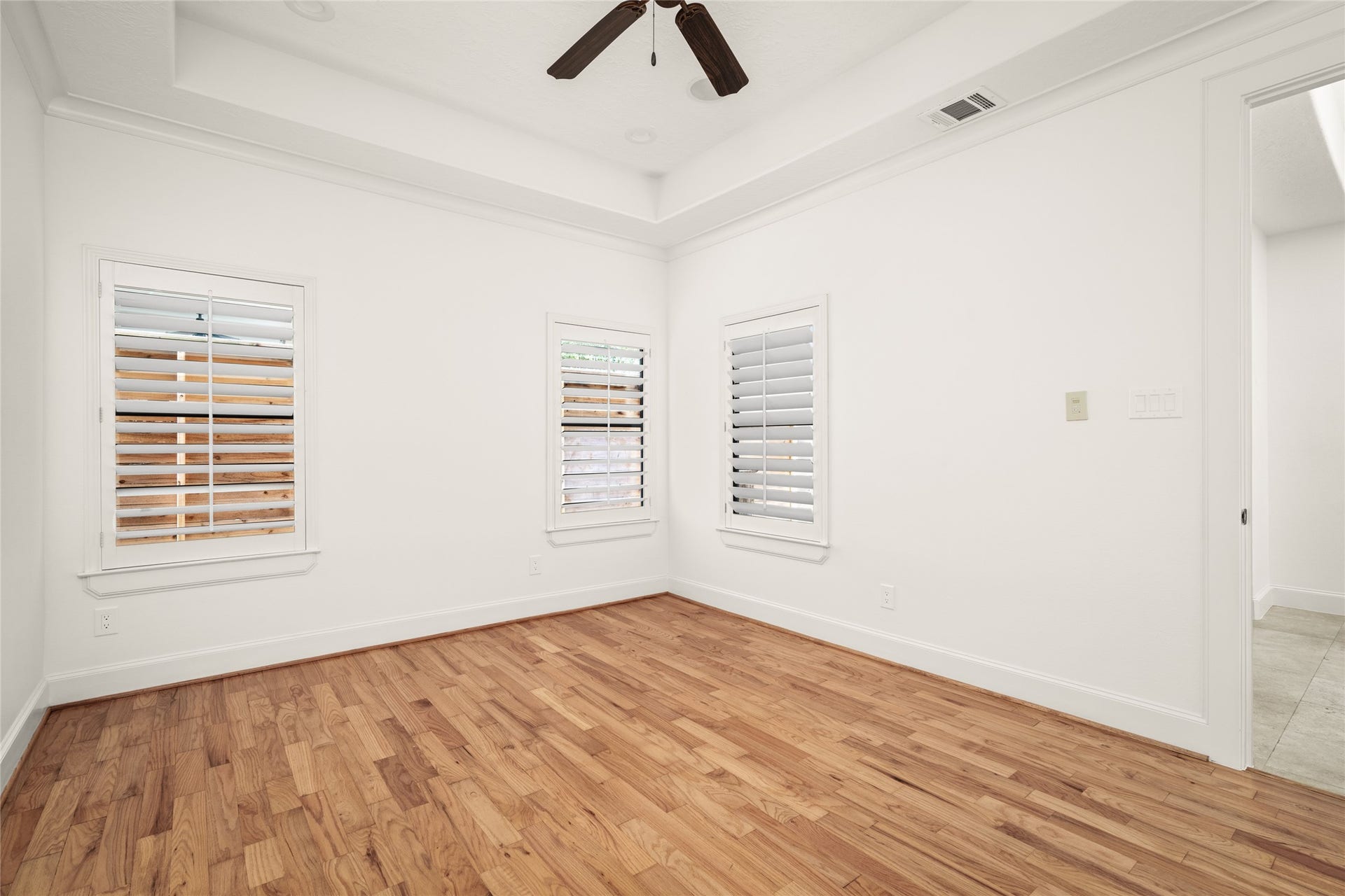 5218 Feagan Street, #D, Houston, TX 77007 First floor bedroom with tray ceilings, recessed lighting, hardwood flooring, a full bathroom and a walk in closet.