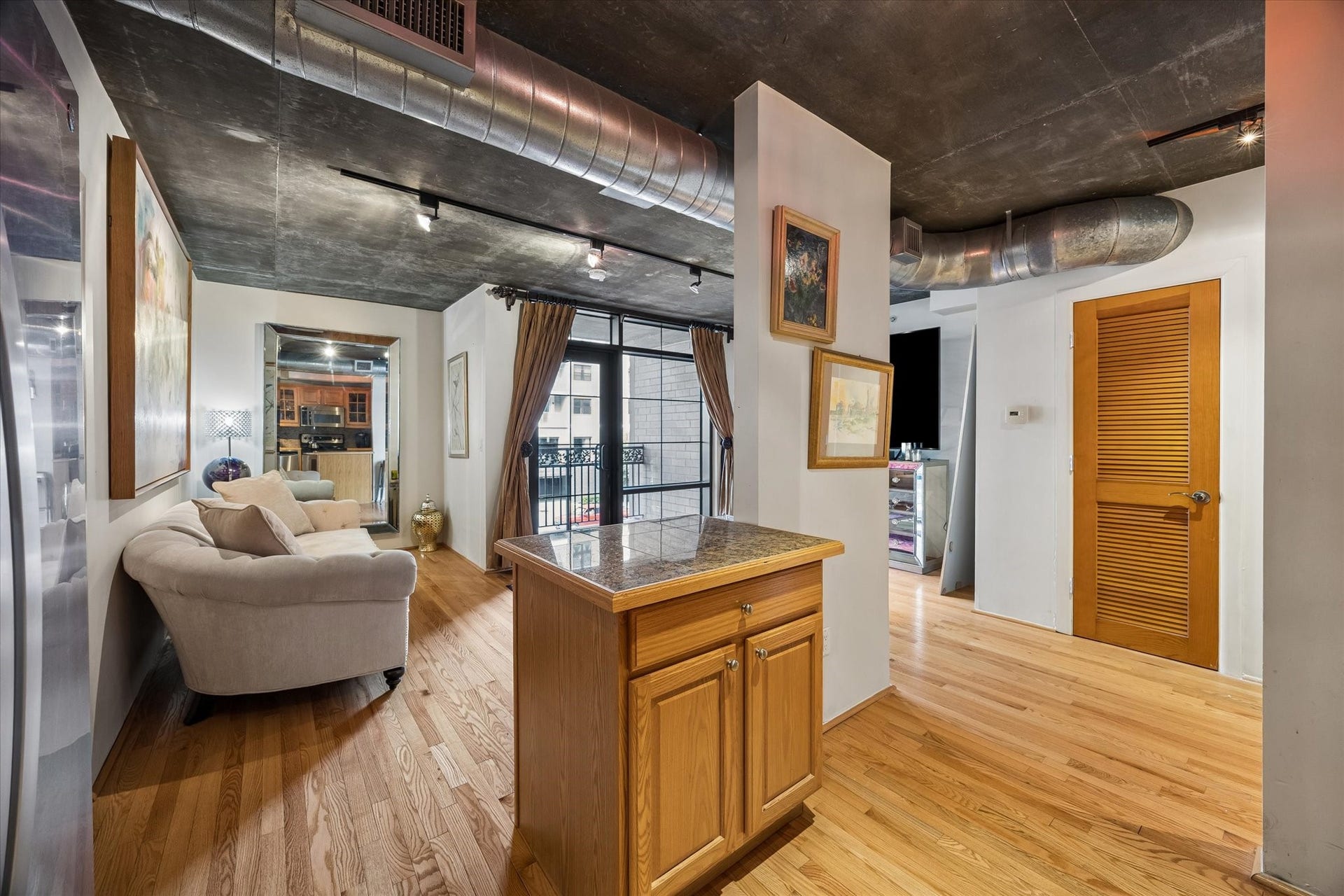 An open-concept layout connects the kitchen and living area, creating a comfortable space for relaxing or entertaining. Hardwood flooring, exposed structural elements, and natural light enhance the home's contemporary character.