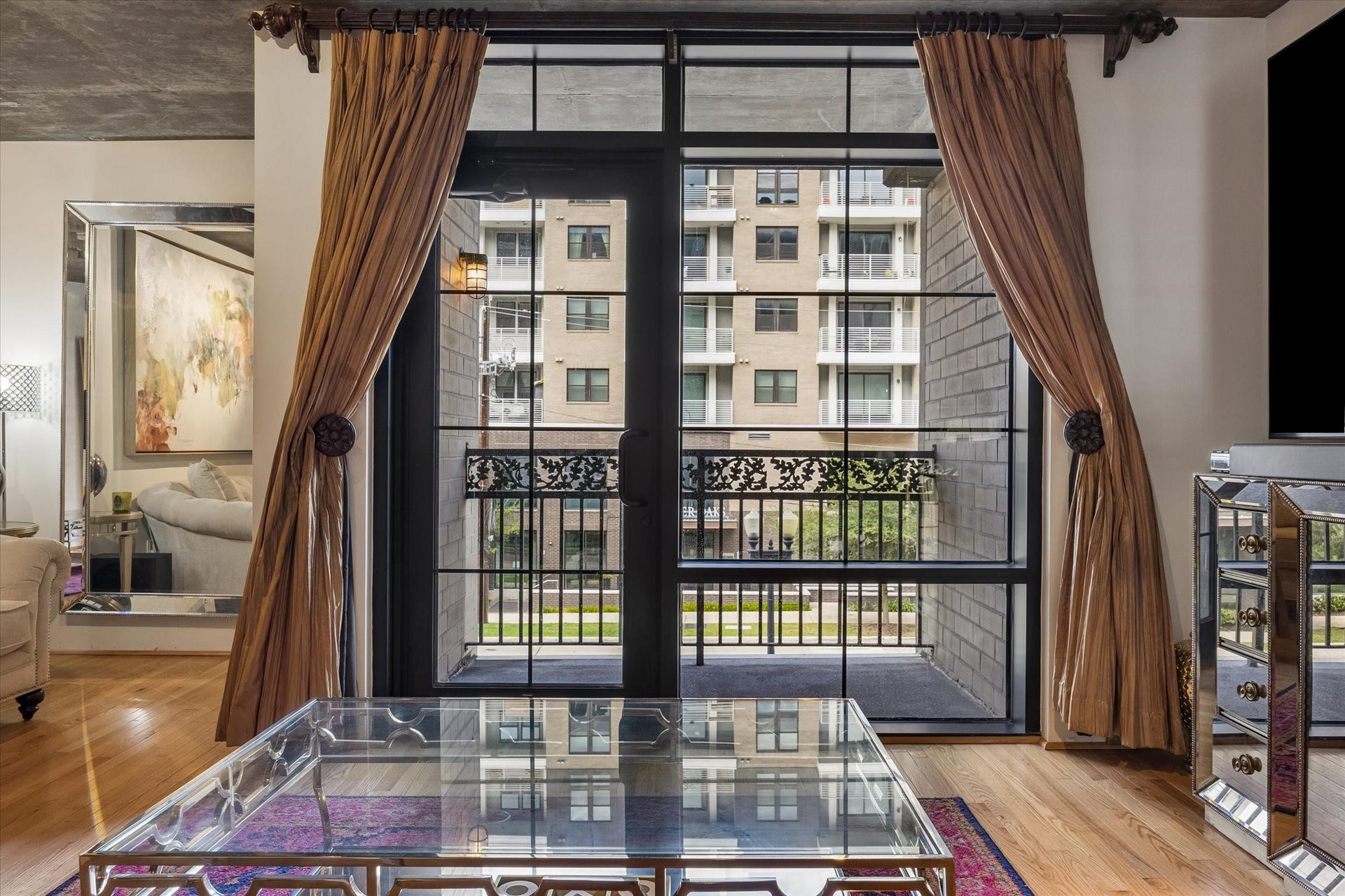 A striking commercial-style glass door adds a modern, industrial touch to the residence while inviting natural light into the living space. Opening to a private balcony, it creates a seamless connection between indoor and outdoor living.