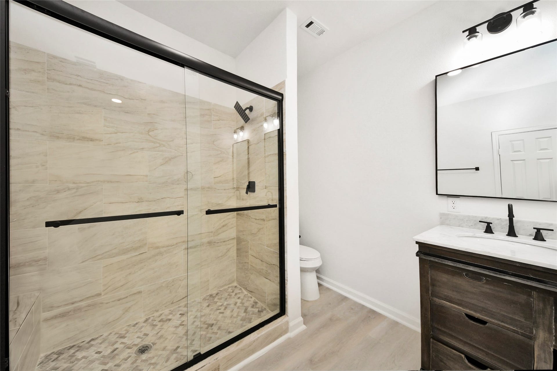 4615 Collingsworth Street, #AB, Houston, TX 77026 Sleek bathroom featuring a spacious glass-enclosed shower with elegant tilework, modern fixtures, and a stylish vanity with a large mirror.