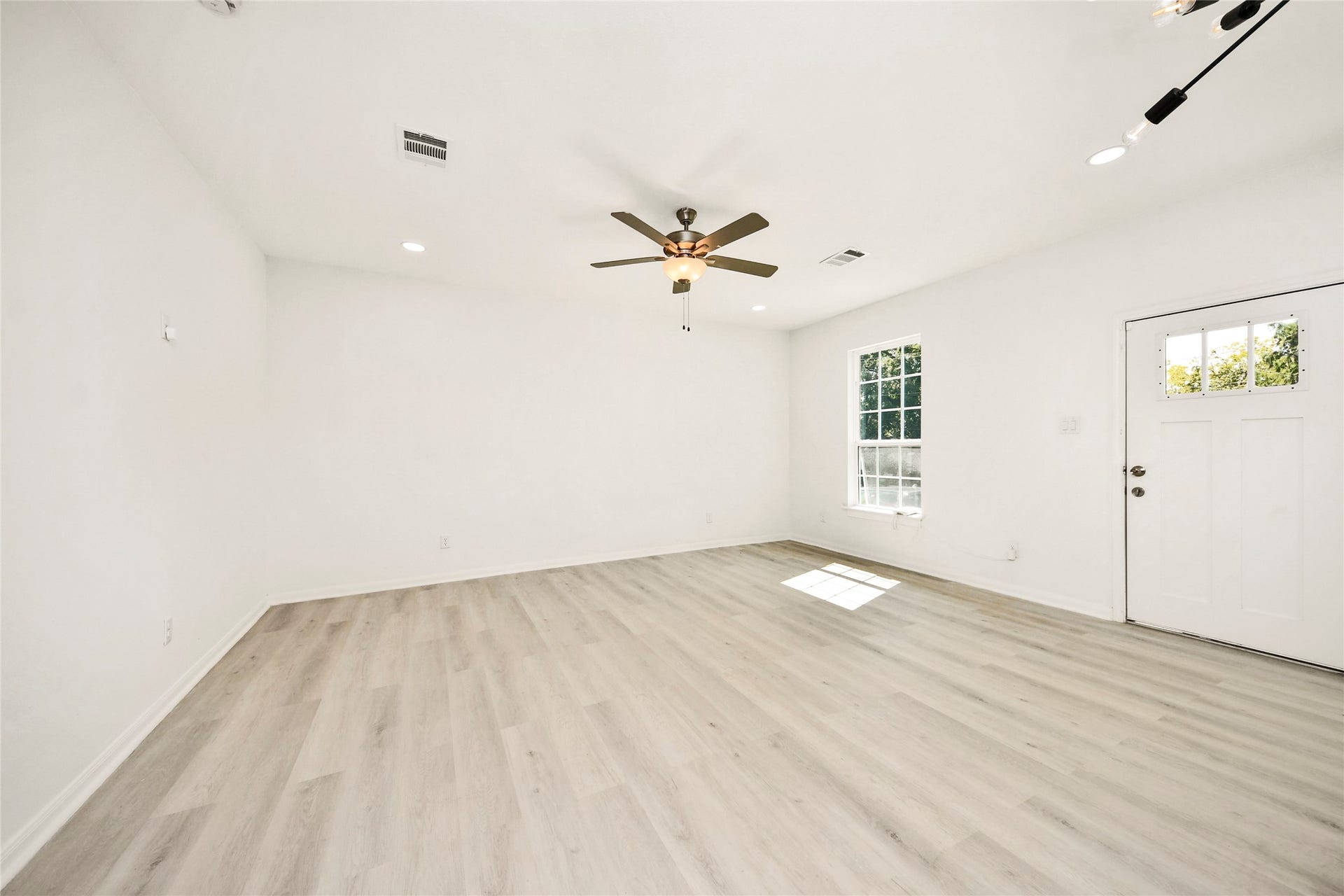4615 Collingsworth Street, #AB, Houston, TX 77026 Spacious living area with light wood flooring, a ceiling fan, and abundant natural light from the large window, creating a bright and welcoming atmosphere.