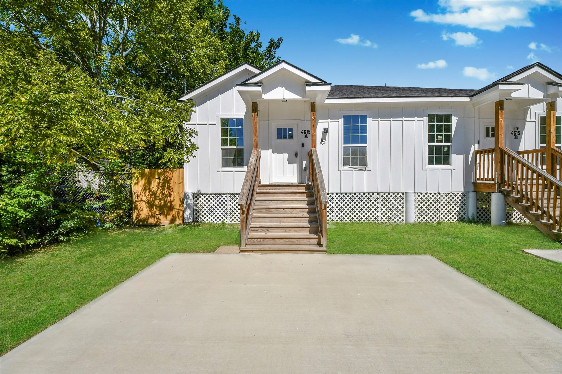 4615 Collingsworth Street, #AB, Houston, TX 77026 Charming duplex with a clean, modern exterior featuring a white facade and cozy wooden porch steps, set against a lush green backdrop.