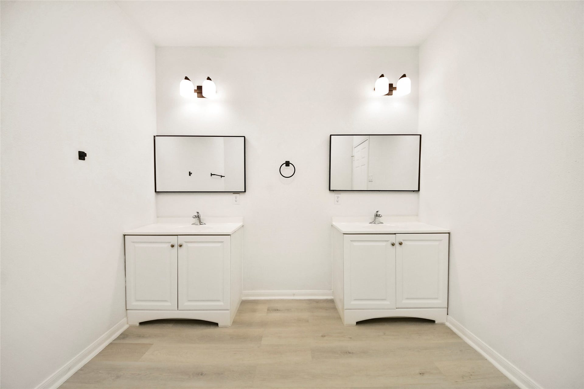 4615 Collingsworth Street, #AB, Houston, TX 77026 Bright, minimalist bathroom featuring dual vanities with sleek white cabinetry, modern fixtures, and elegant lighting.