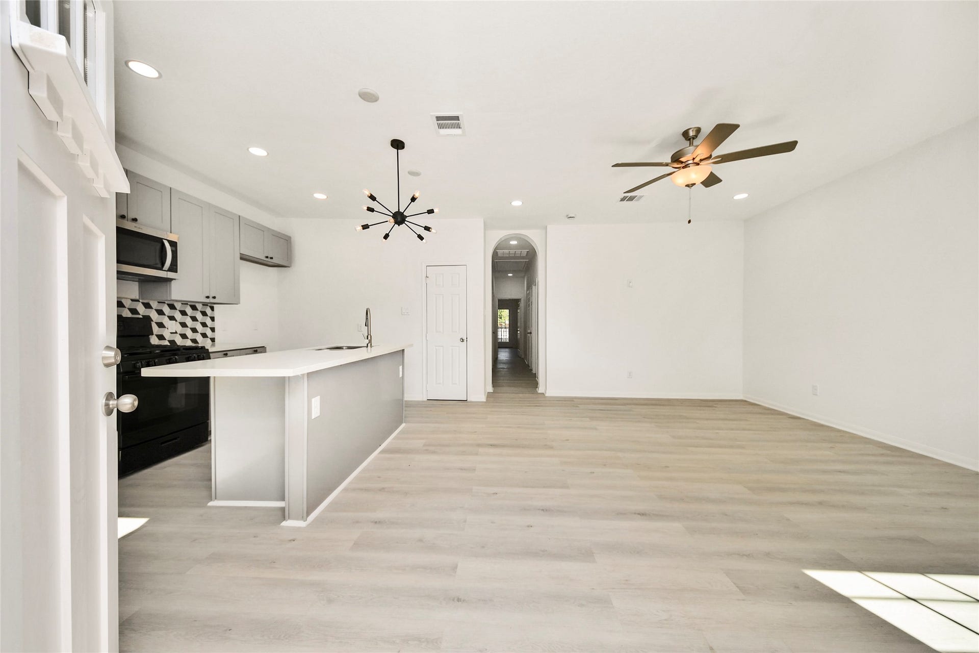 4615 Collingsworth Street, #AB, Houston, TX 77026 Experience modern living in this open-concept space featuring a sleek kitchen with stainless steel appliances, an elegant backsplash, and an island. The bright room offers ample space and is enhanced by stylish light fixtures and a ceiling fan.