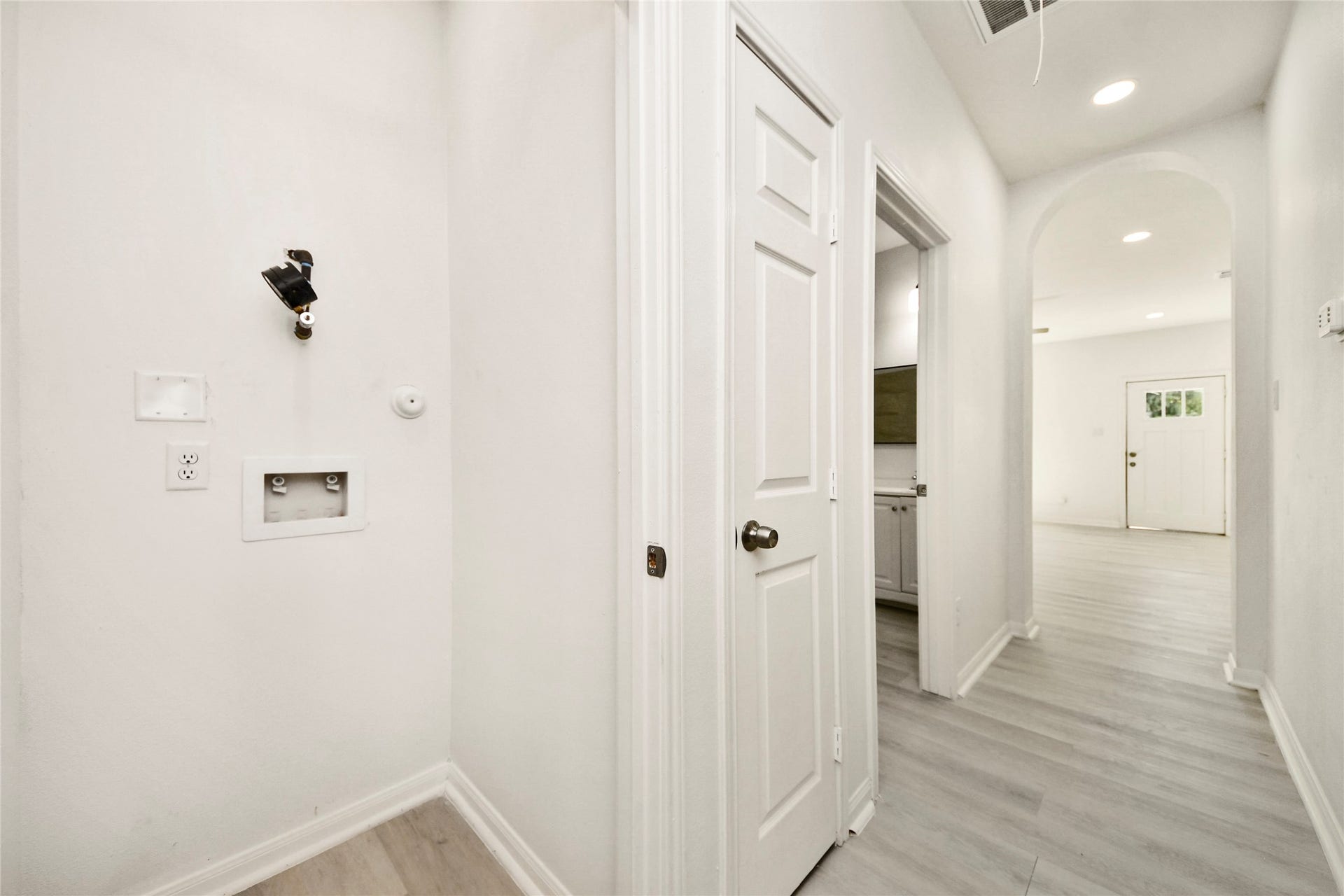 4615 Collingsworth Street, #AB, Houston, TX 77026 Bright hallway with sleek light wood flooring, leading to a room with a door and convenient laundry hookups.