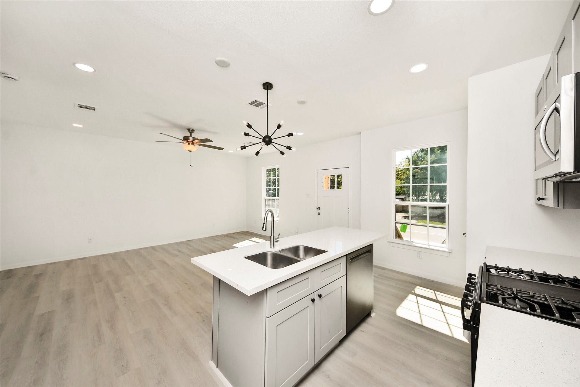4615 Collingsworth Street, #AB, Houston, TX 77026 Bright and open living space features a modern kitchen with a central island, stainless steel appliances, and large windows allowing natural light to flow throughout.
