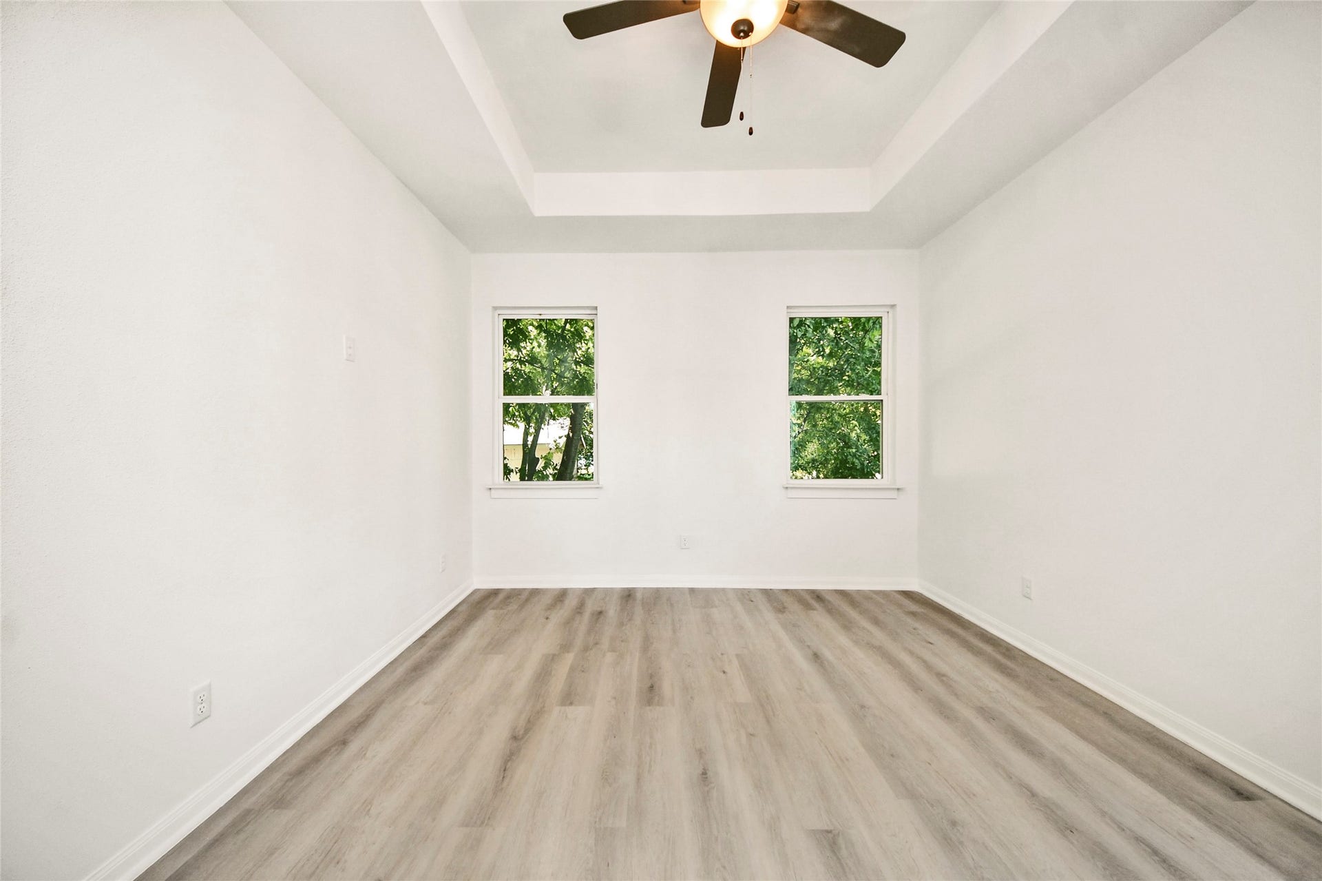 4615 Collingsworth Street, #AB, Houston, TX 77026 Bright, airy room featuring a tray ceiling and modern ceiling fan, with large windows that invite natural light and showcase serene outdoor views.