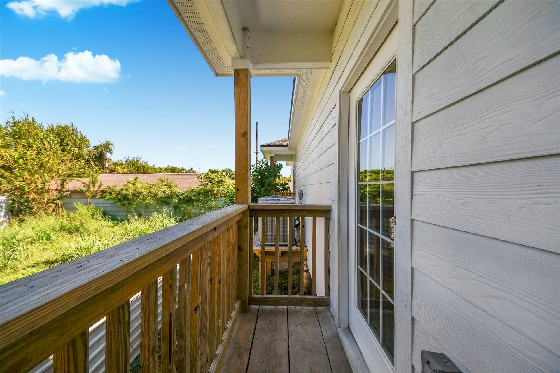 4615 Collingsworth Street, #AB, Houston, TX 77026 Charming balcony with wooden railing offers a serene outdoor space and a lovely view of lush greenery.