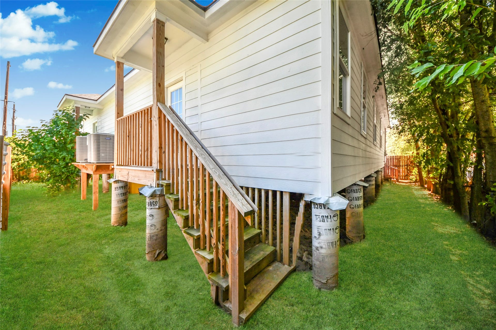 4615 Collingsworth Street, #AB, Houston, TX 77026 Charming elevated home with a cozy wooden porch and stairs, surrounded by lush greenery for a serene outdoor experience.