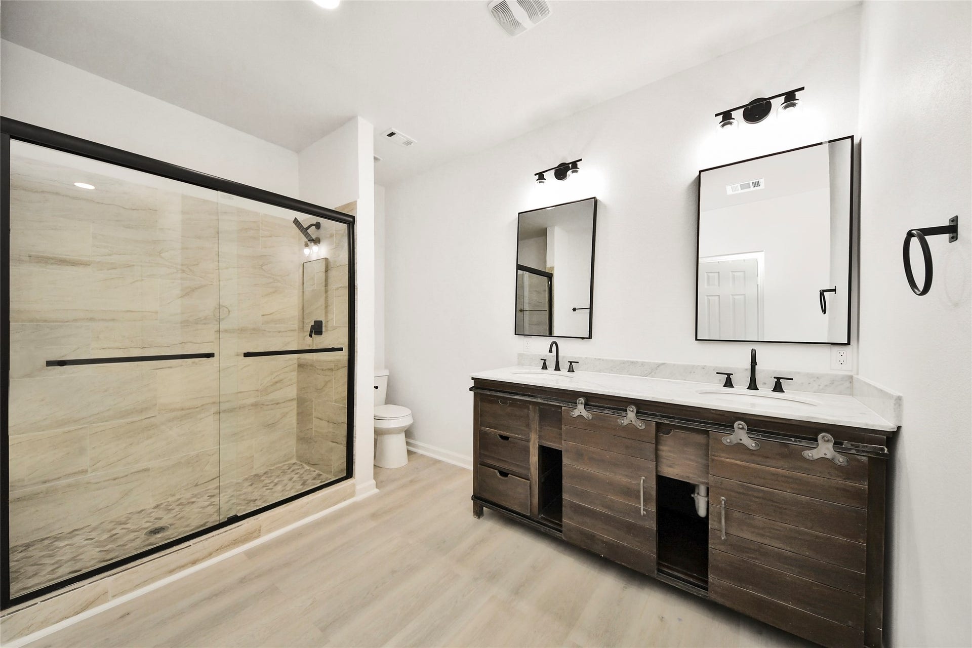 4615 Collingsworth Street, #AB, Houston, TX 77026 Elegant bathroom featuring a spacious glass-enclosed shower, dual vanity sinks with modern fixtures, and stylish wood accents for a luxurious touch.